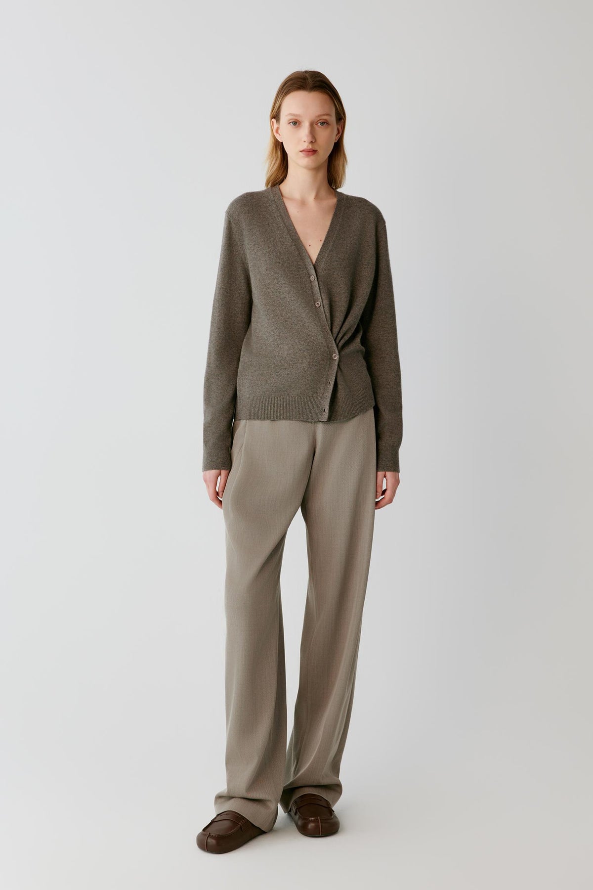 Front full-length view of a woman wearing the taupe cashmere wrap cardigan, highlighting the asymmetric front and fitted silhouette.