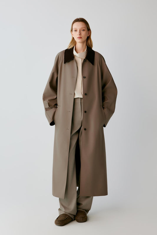 Front view of a woman wearing a dusty brown wool and silk trench coat, showing the long silhouette, contrasting dark brown corduroy collar and single-breasted front.