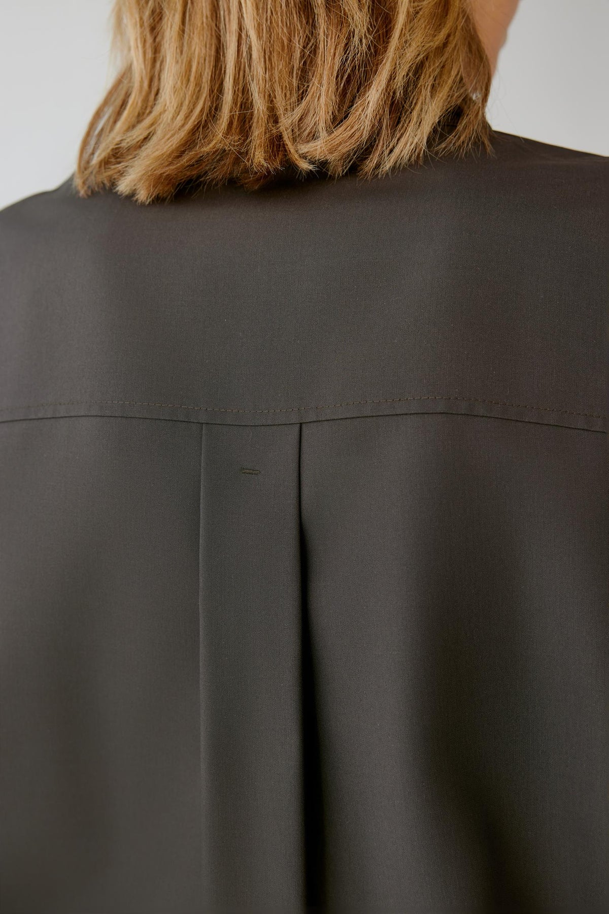 Close-up highlighting the back pleat and smooth walnut brown silk poplin surface.
