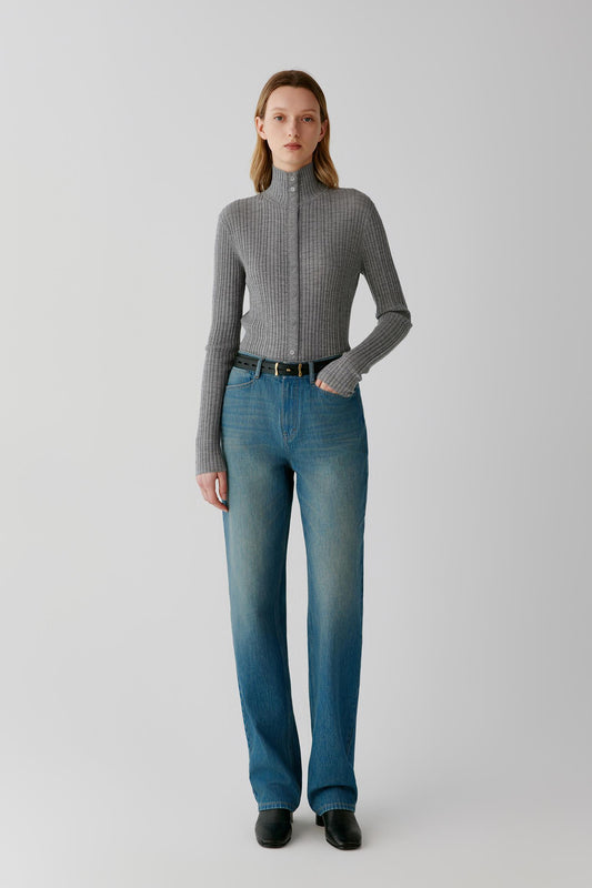 Front view of a woman wearing a grey melange worsted wool cardigan, showing the close-fitting silhouette, stand collar and button-front fastening.