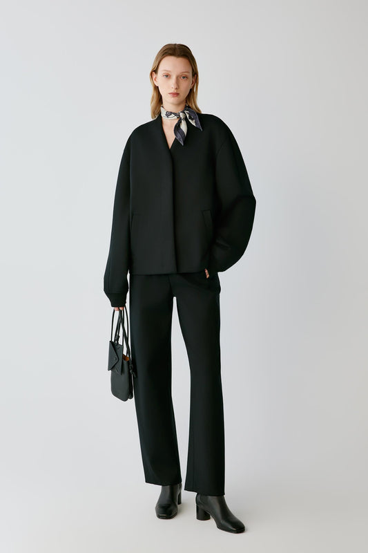 Front view of a woman wearing deep black Ponte wool trousers, showing the straight-leg silhouette and clean drape.