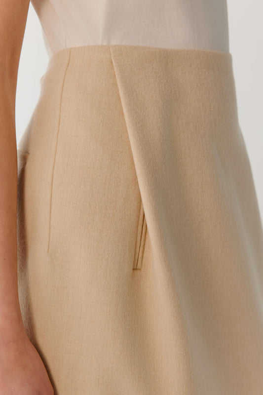 Close-up highlighting the clean side construction and smooth double-face wool surface of the beige melange skirt.