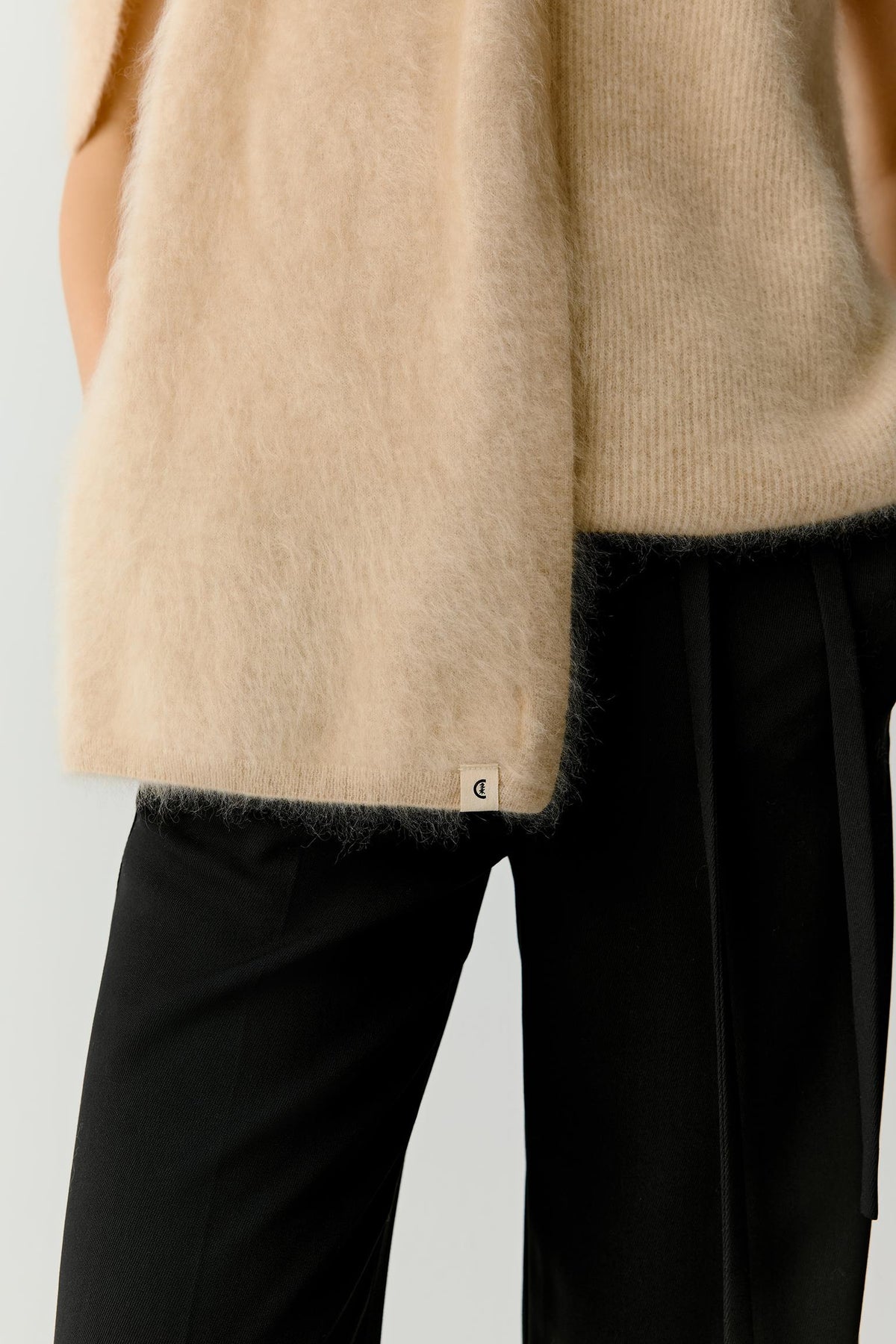 Close-up of the scarf hanging vertically along the body, highlighting the fluid fall of the fabric, clean edges and soft folds. The image showcases the subtle tonal depth and lightweight structure characteristic of fine cashmere.