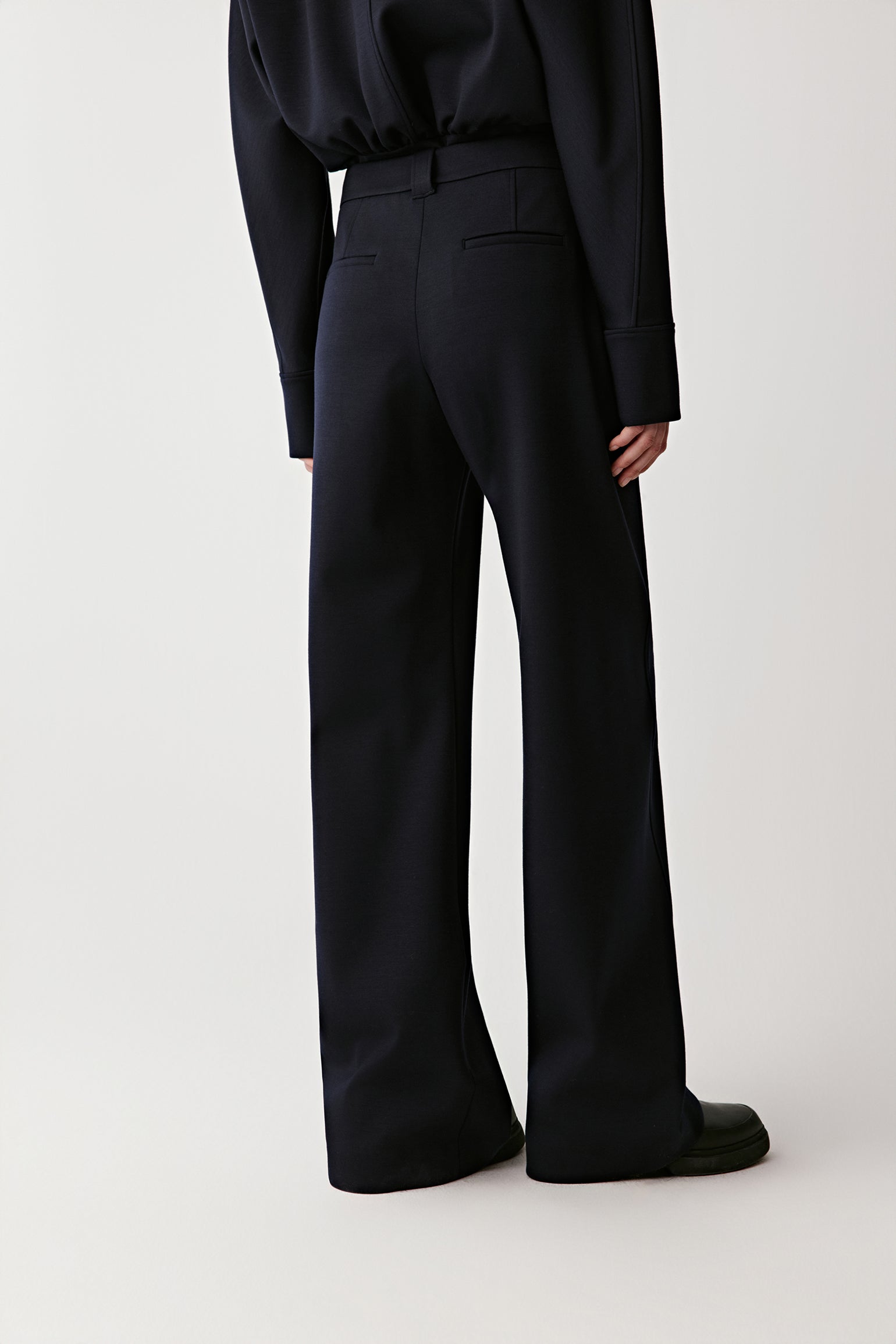 Person wearing black pants and a dark shirt on a white background