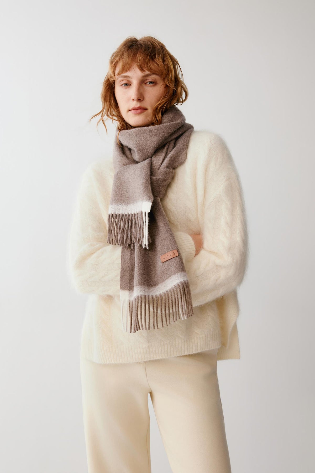 Front view of a woman wearing a dark grey cashmere scarf with contrasting light grey trim and fringed edges.