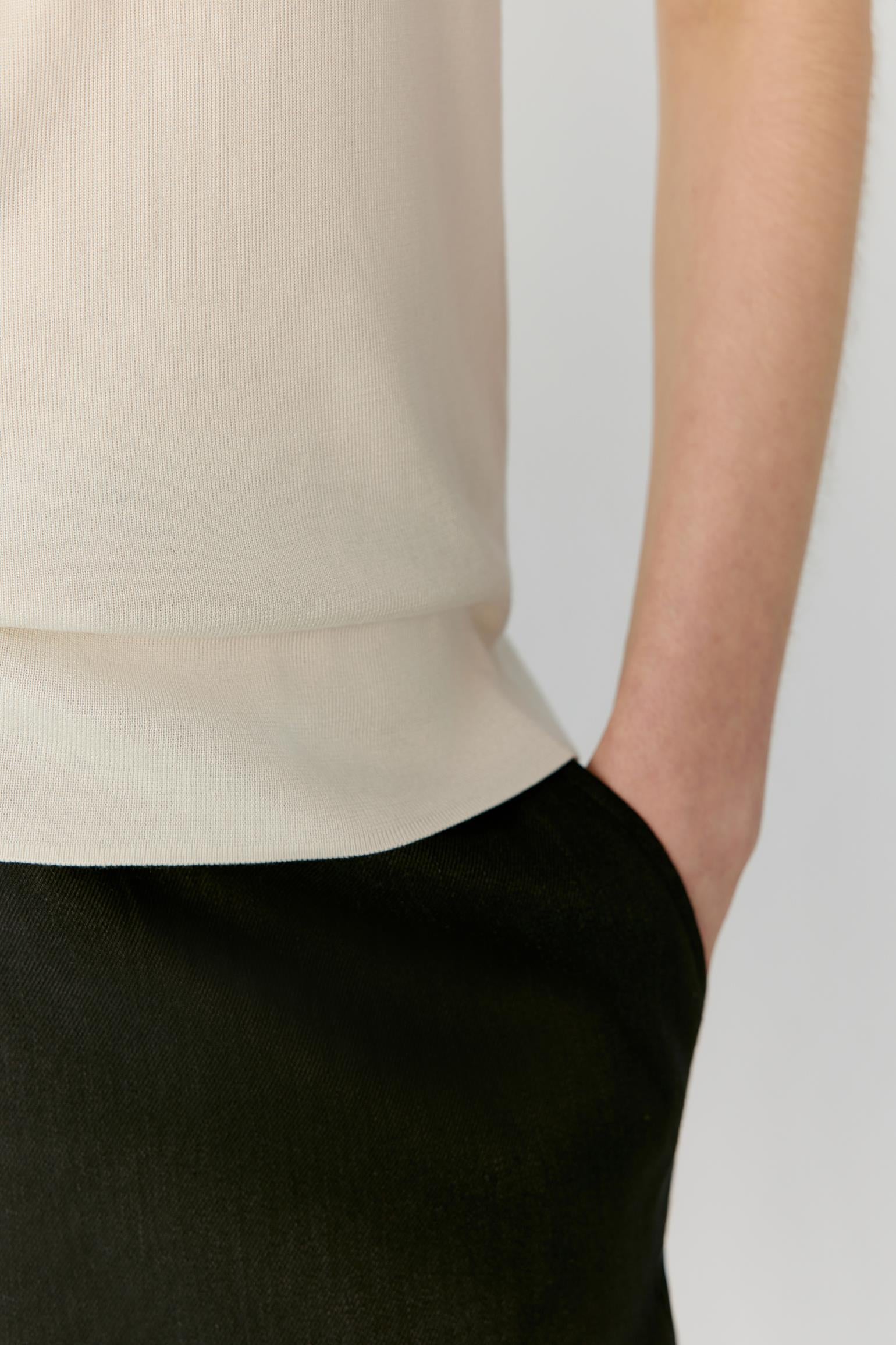 Close-up of the lower body highlighting the clean hem finishing and smooth texture of the fine-gauge silk knit. The image reveals the lightweight structure, soft hand and fluid drape where the top meets the trousers.