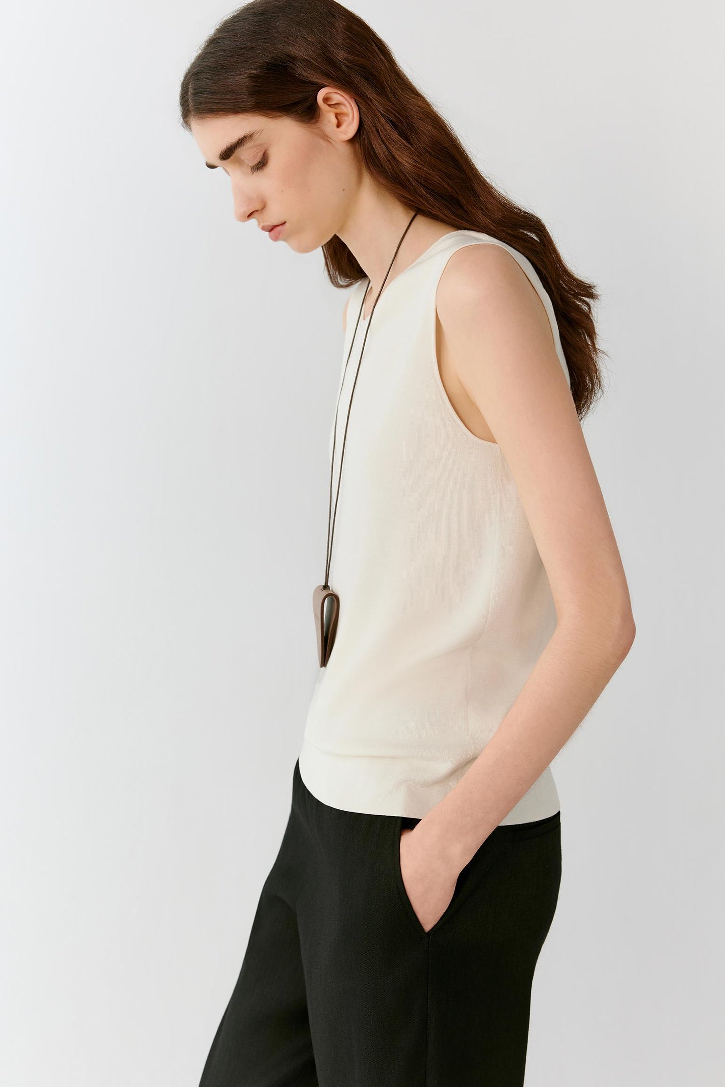 Side view highlighting the straight silhouette, sleeveless construction and fluid fall of the lightweight silk knit. The image emphasizes the clean side line and the natural movement of the fabric.
