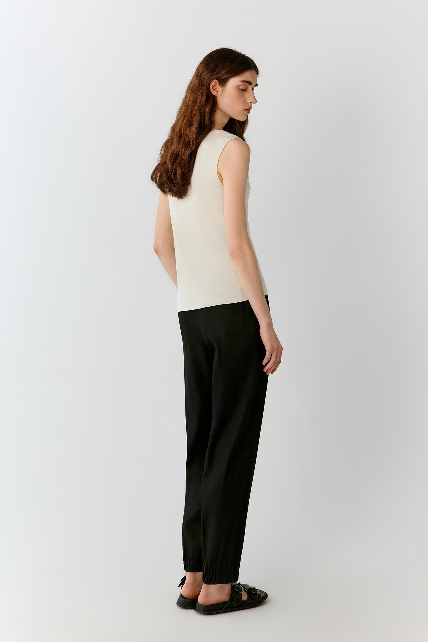 Three-quarter rear view highlighting the clean back construction, round neckline and balanced proportions of the sleeveless silhouette. The image emphasizes the smooth surface, lightweight knit and understated elegance of the garment.