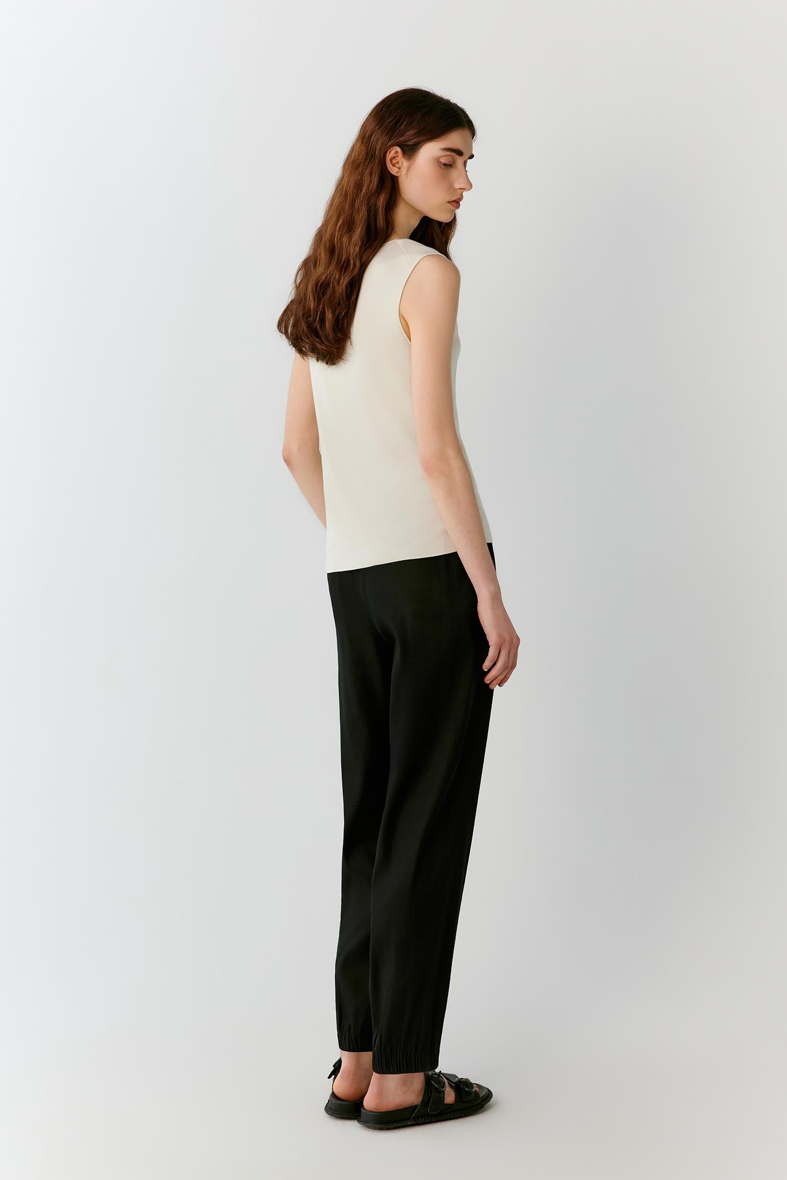 Three-quarter rear view highlighting the clean back construction, round neckline and balanced proportions of the sleeveless silhouette. The image emphasizes the smooth surface, lightweight knit and understated elegance of the garment.
