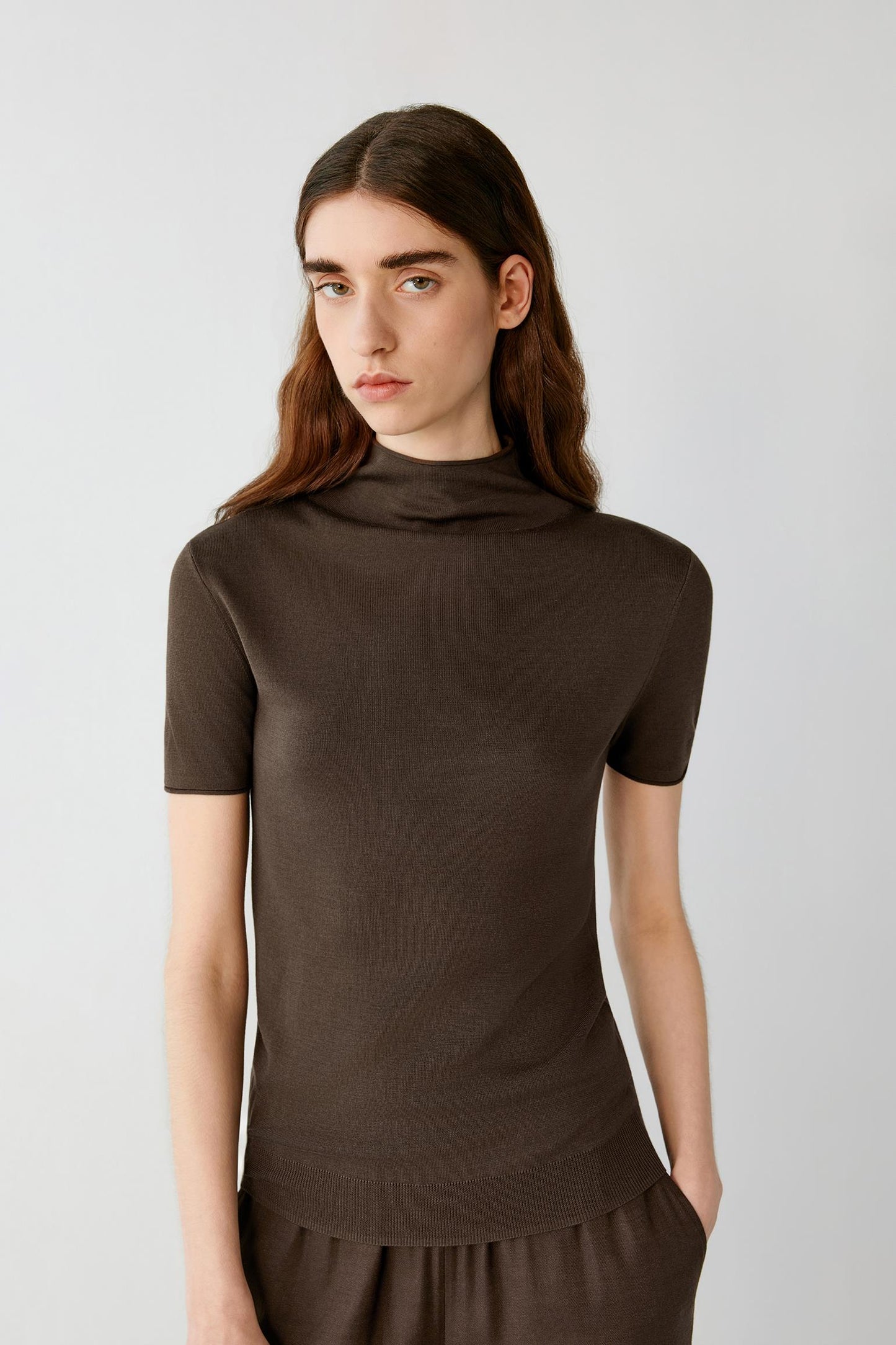 Three-quarter view showing the fitted shape and the natural drape of the fine-gauge silk knit. The image emphasizes the mock neckline, fine ribbed finishes and the clean structure of the garment.