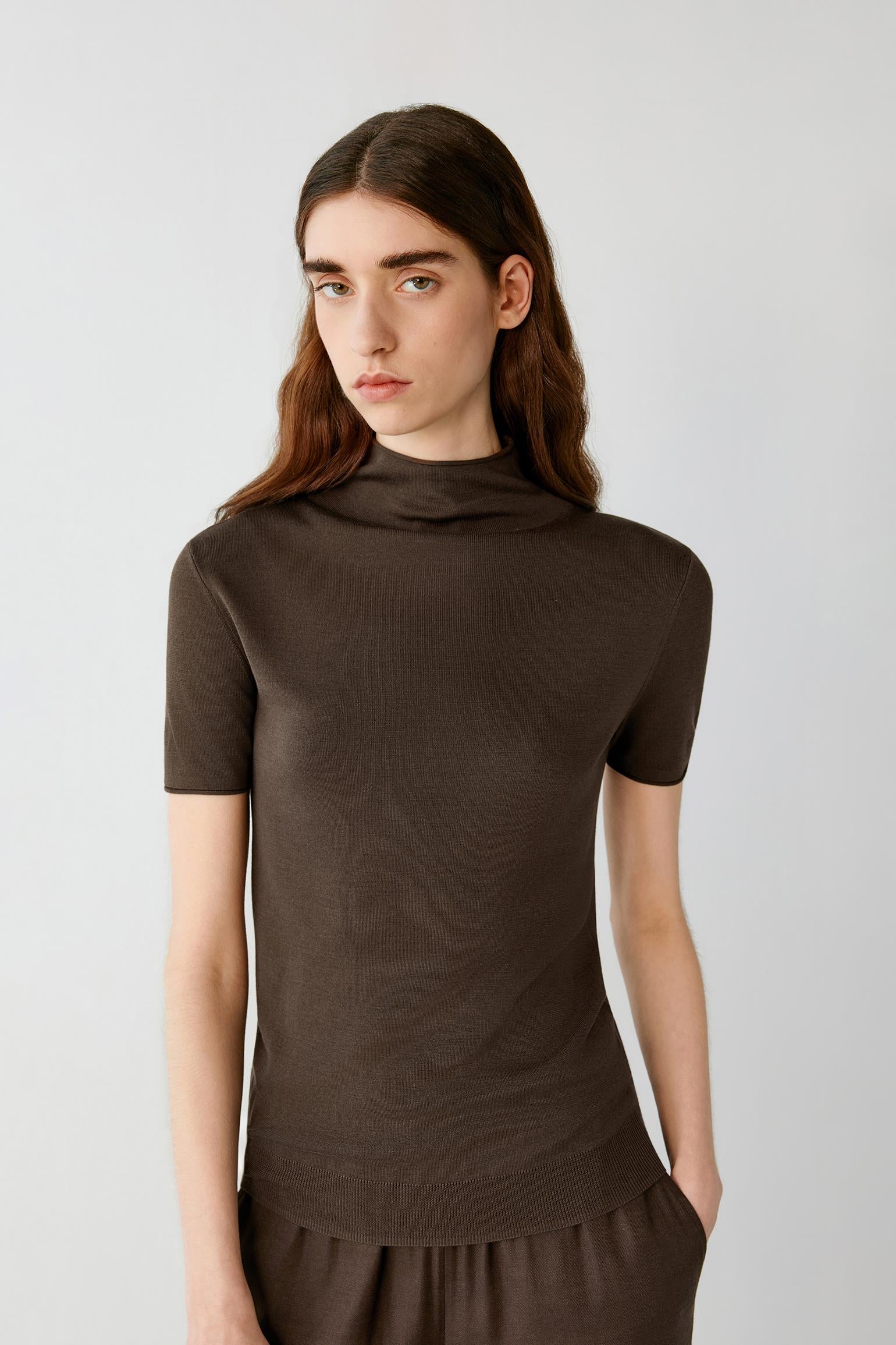 Three-quarter view showing the fitted shape and the natural drape of the fine-gauge silk knit. The image emphasizes the mock neckline, fine ribbed finishes and the clean structure of the garment.