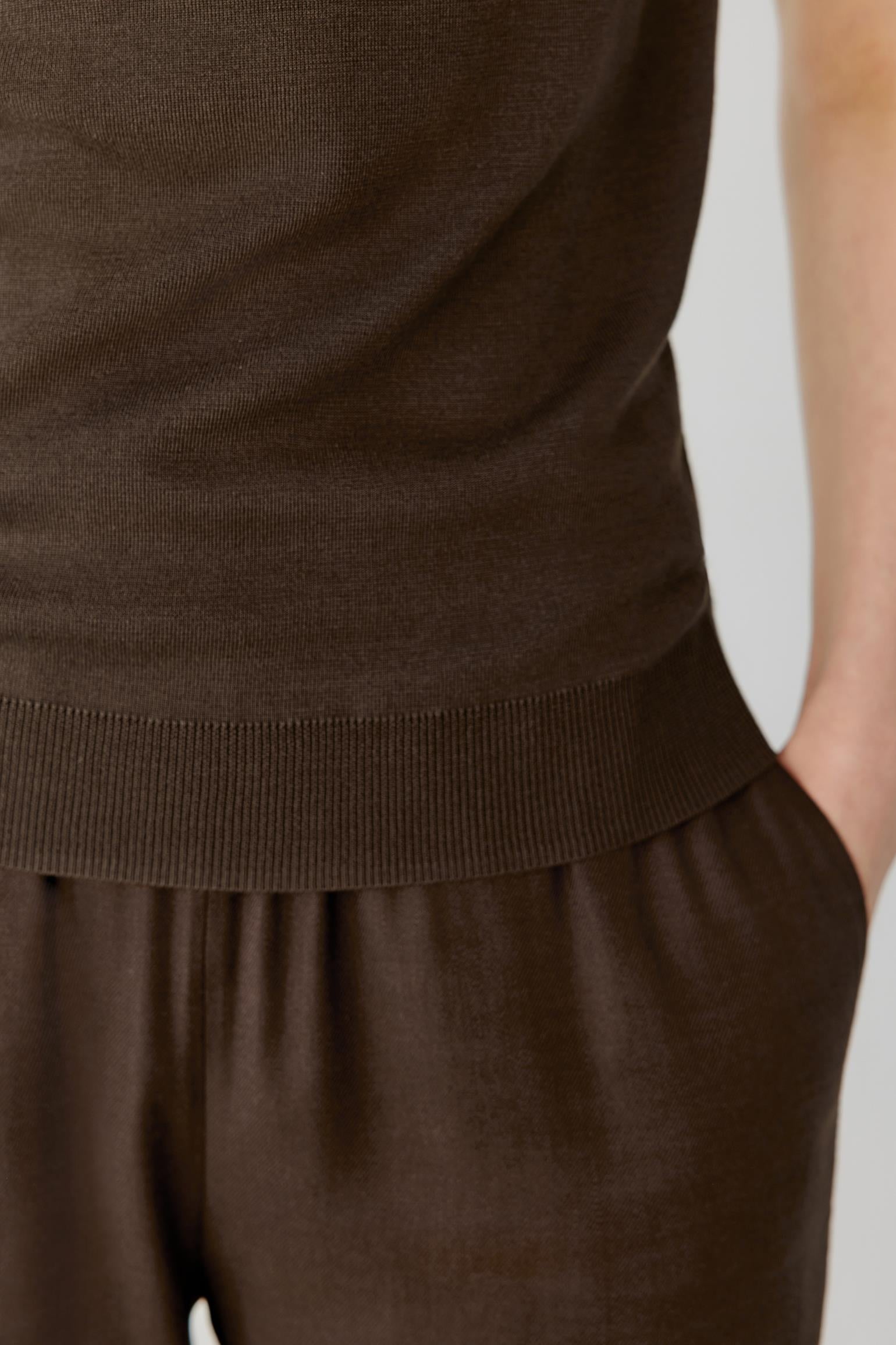 Close-up of the lower body highlighting the fine ribbed hem and the smooth, compact texture of the silk knit. The image emphasizes the clean finishing, lightweight construction and the fluid transition between the top and the matching trousers.