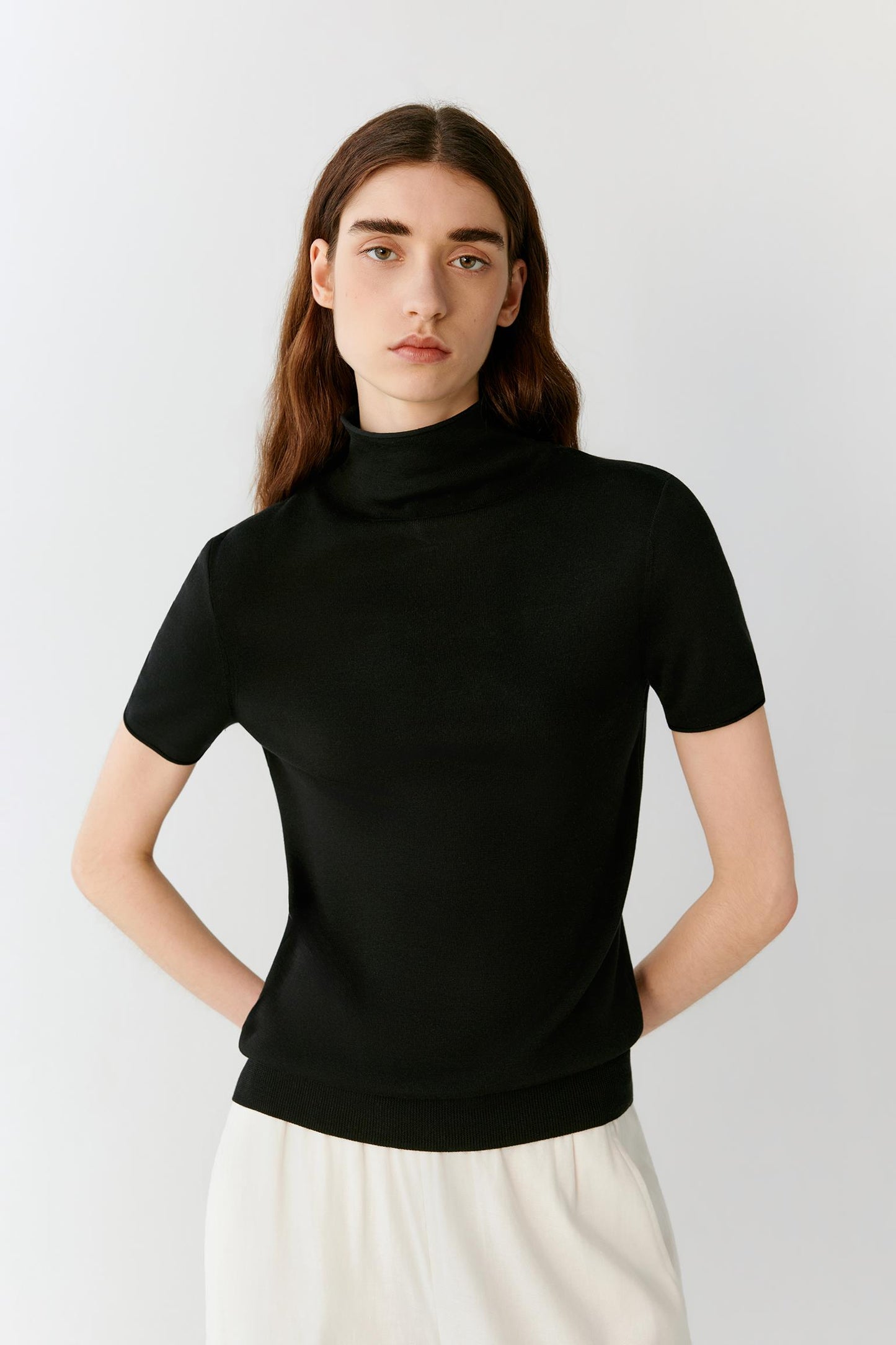 Front view showing the fitted shape and the natural drape of the fine-gauge silk knit. The image emphasizes the mock neckline, fine ribbed finishes and the clean structure of the garment.
