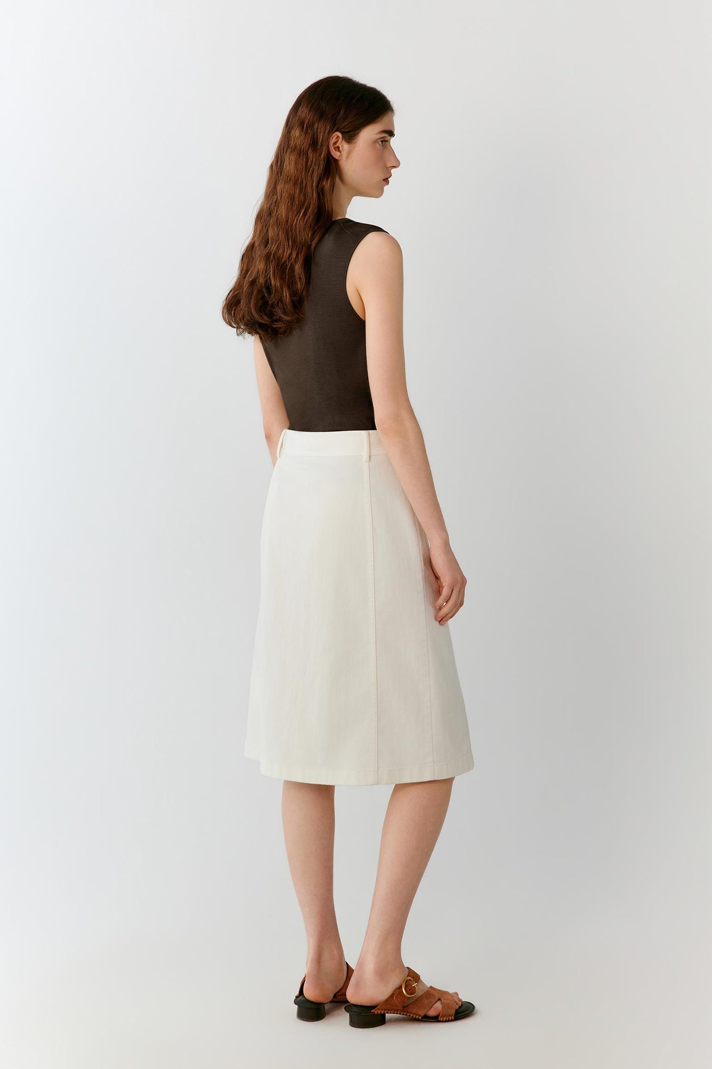 Full-length rear view showing the sleeveless top paired with a midi skirt. The image emphasizes the clean back construction, fluid drape and the way the lightweight silk knit falls naturally over the body.