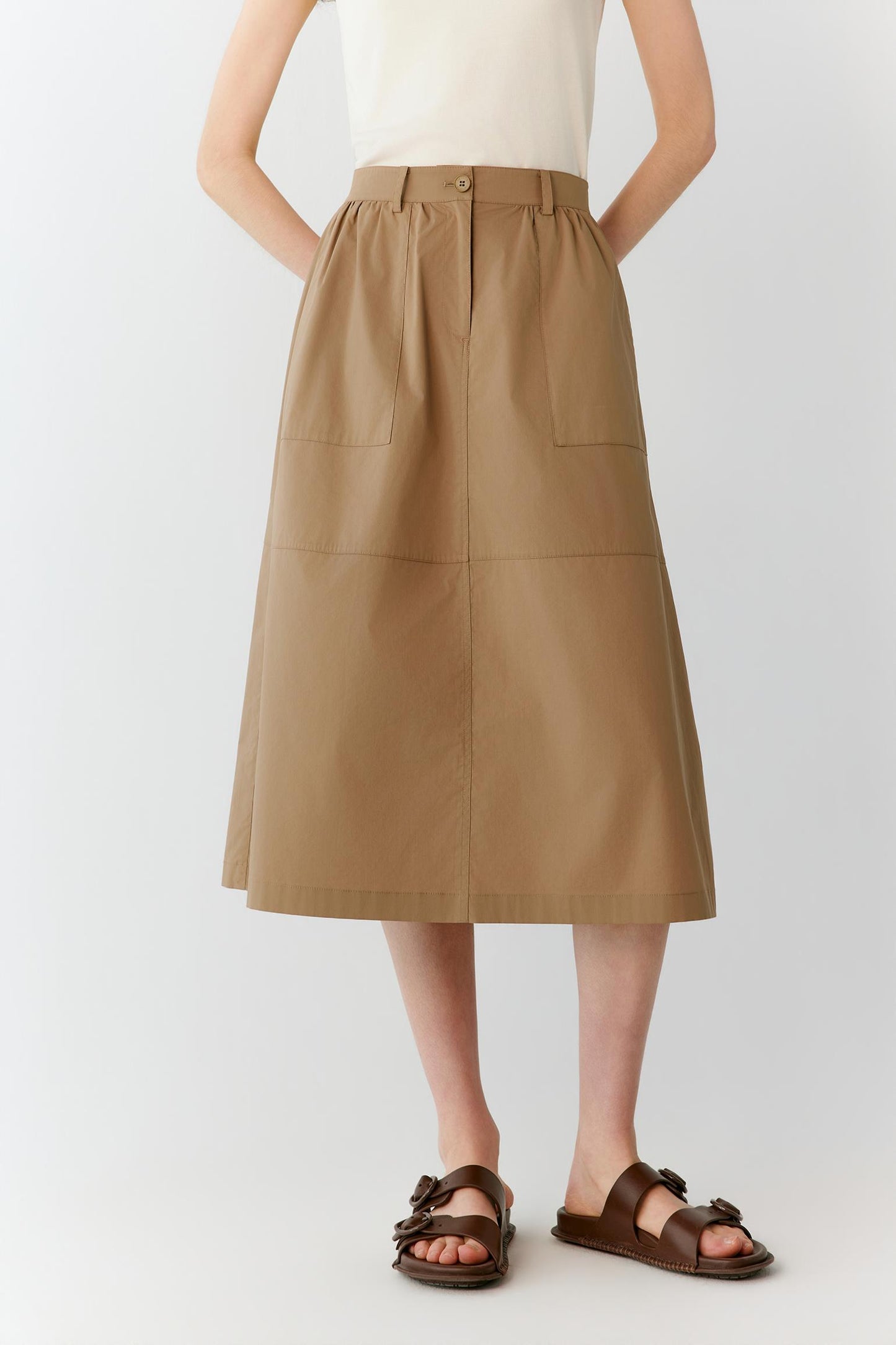 Full-length view focused on the skirt, emphasizing the midi length, softly flared shape and balanced proportions. The image highlights the natural drape of the lightweight cotton blend and the continuous panel construction that enhances the silhouette.