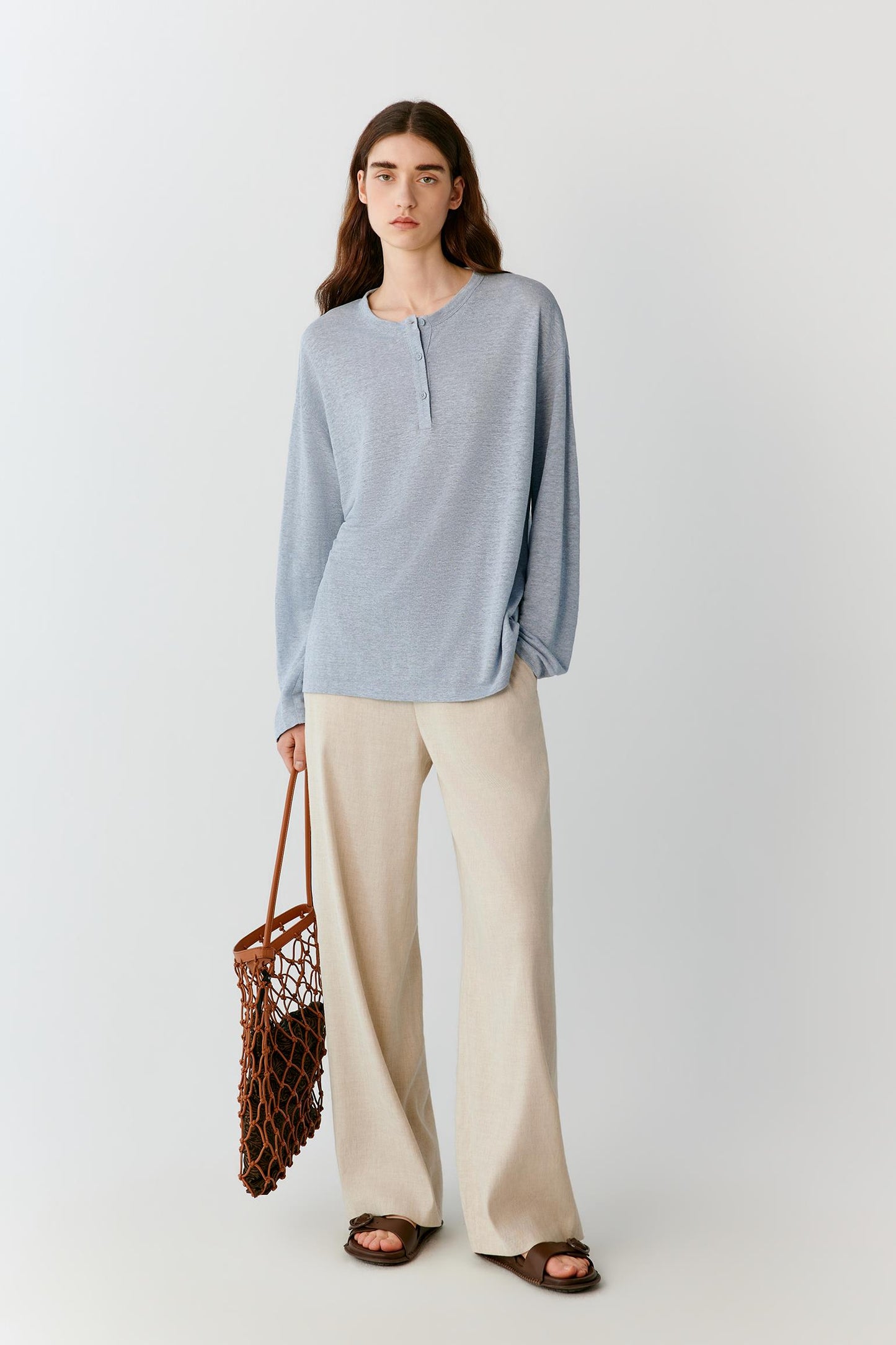 Front view of a woman wearing ivory linen trousers, highlighting the straight-leg silhouette, lightweight construction and fluid drape of the fabric. The clean waistband and smooth front create a refined, understated appearance, while the natural linen texture adds subtle depth to the surface.