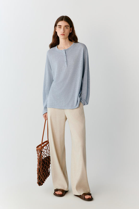 Front view of a woman wearing ivory linen trousers, highlighting the straight-leg silhouette, lightweight construction and fluid drape of the fabric. The clean waistband and smooth front create a refined, understated appearance, while the natural linen texture adds subtle depth to the surface.