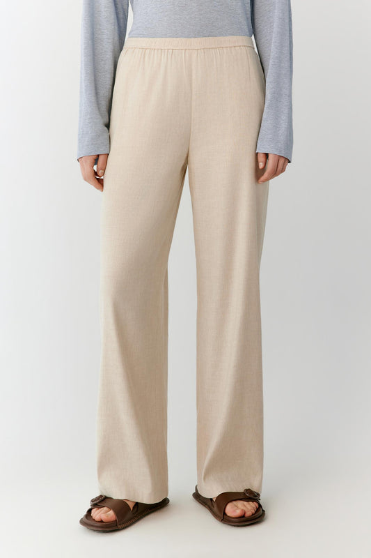 Full-length view focused on the trousers, emphasizing the straight-leg cut, long proportions and soft movement of the lightweight linen fabric. The image highlights the fluid fall from the waistband to the hem and the clean, balanced silhouette.