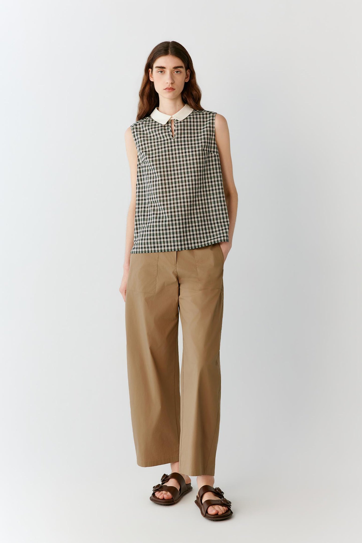 Front view of a woman wearing brown trousers in a cotton blend, highlighting the straight-leg silhouette, lightweight construction and smooth surface of the fabric. The clean waistband and fluid drape create a balanced, understated appearance, while subtle tonal variations add depth to the material.