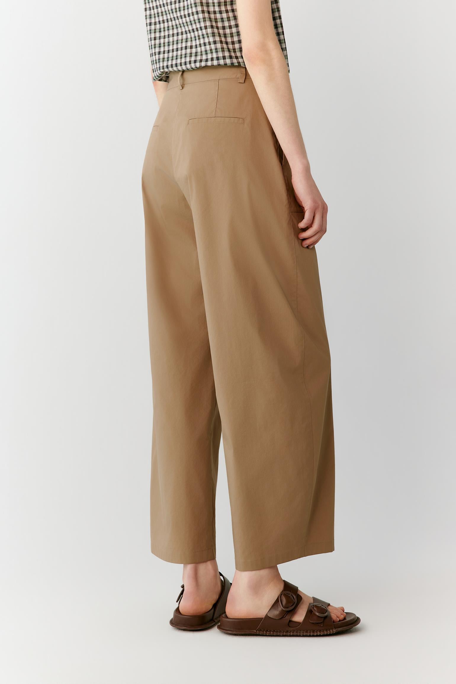 Side view highlighting the clean straight-leg construction and the soft drape of the fabric. The image reveals the smooth side seam, elongated silhouette and lightweight structure that allows the trousers to move naturally.