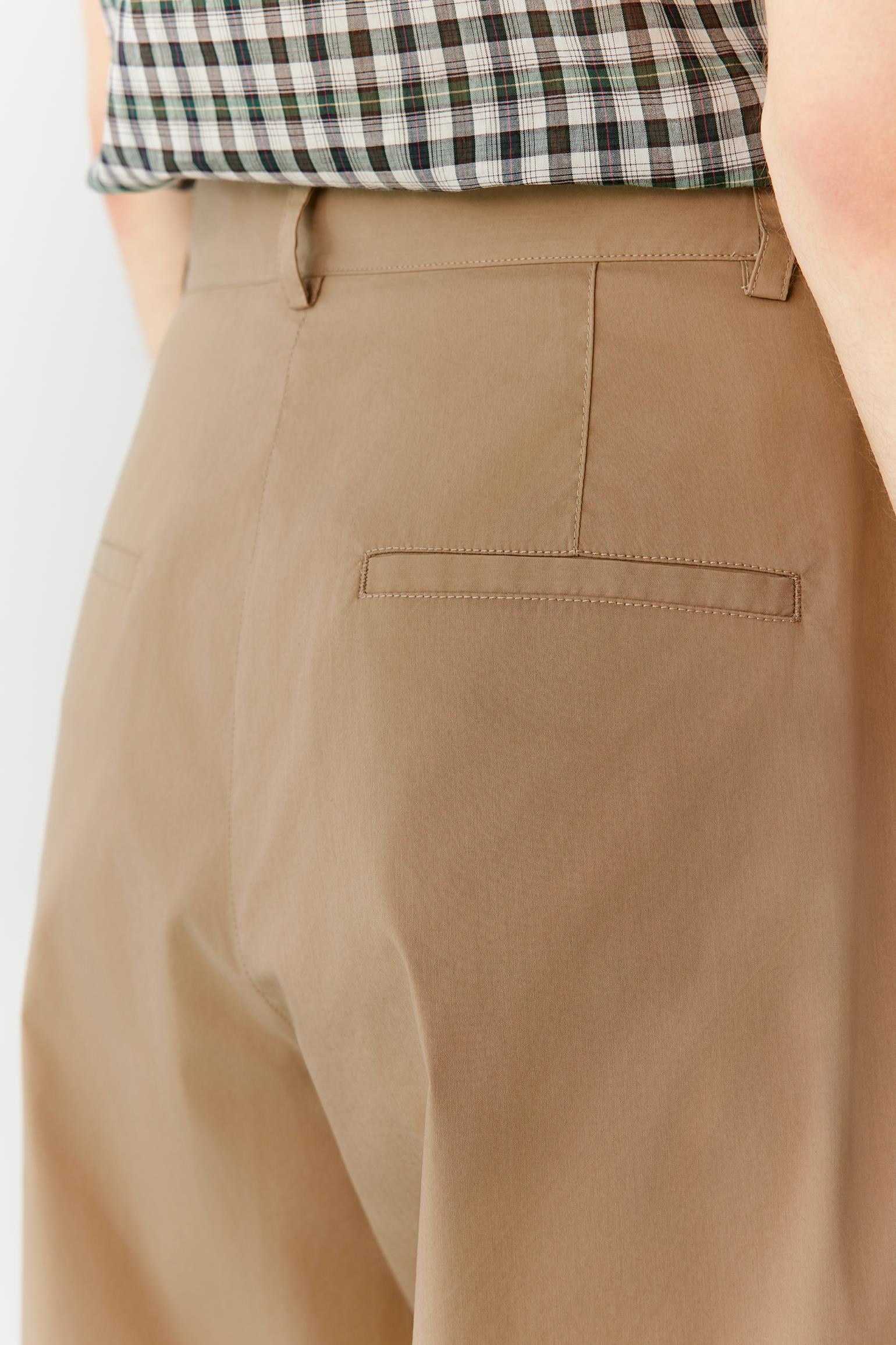 Close-up of the waistband and upper front construction, revealing the clean finishing, front fastening and smooth texture of the cotton blend fabric. The image highlights the precise tailoring and subtle tonal depth of the brown material.