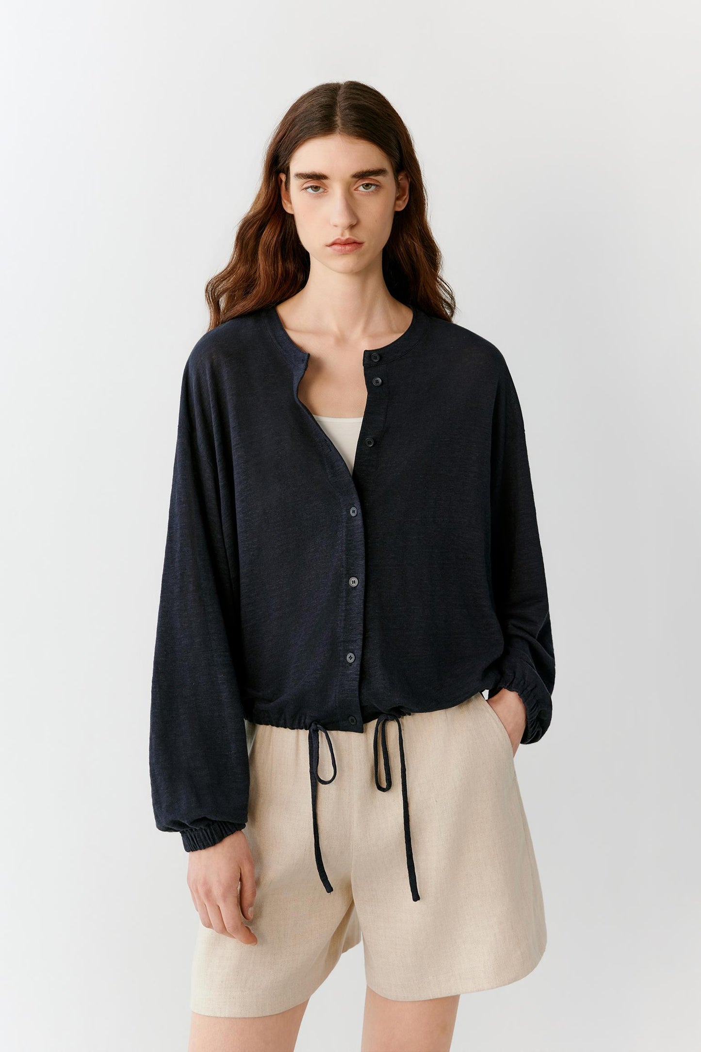 Three-quarter view showing the relaxed fit and natural movement of the lightweight linen blend jersey. The image emphasizes the cropped proportions, soft drape and minimal construction of the jacket.