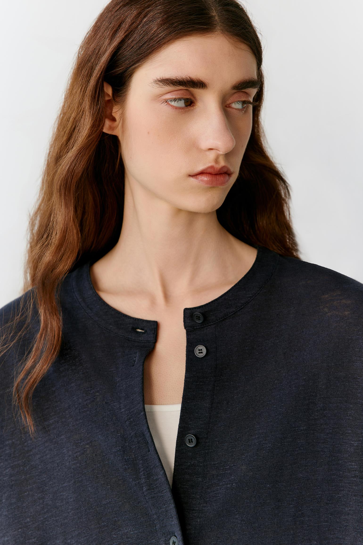 Close-up portrait focusing on the round neckline, front zip fastening and upper body construction. The image reveals the smooth texture, lightweight jersey structure and refined finishing of the deep navy fabric.