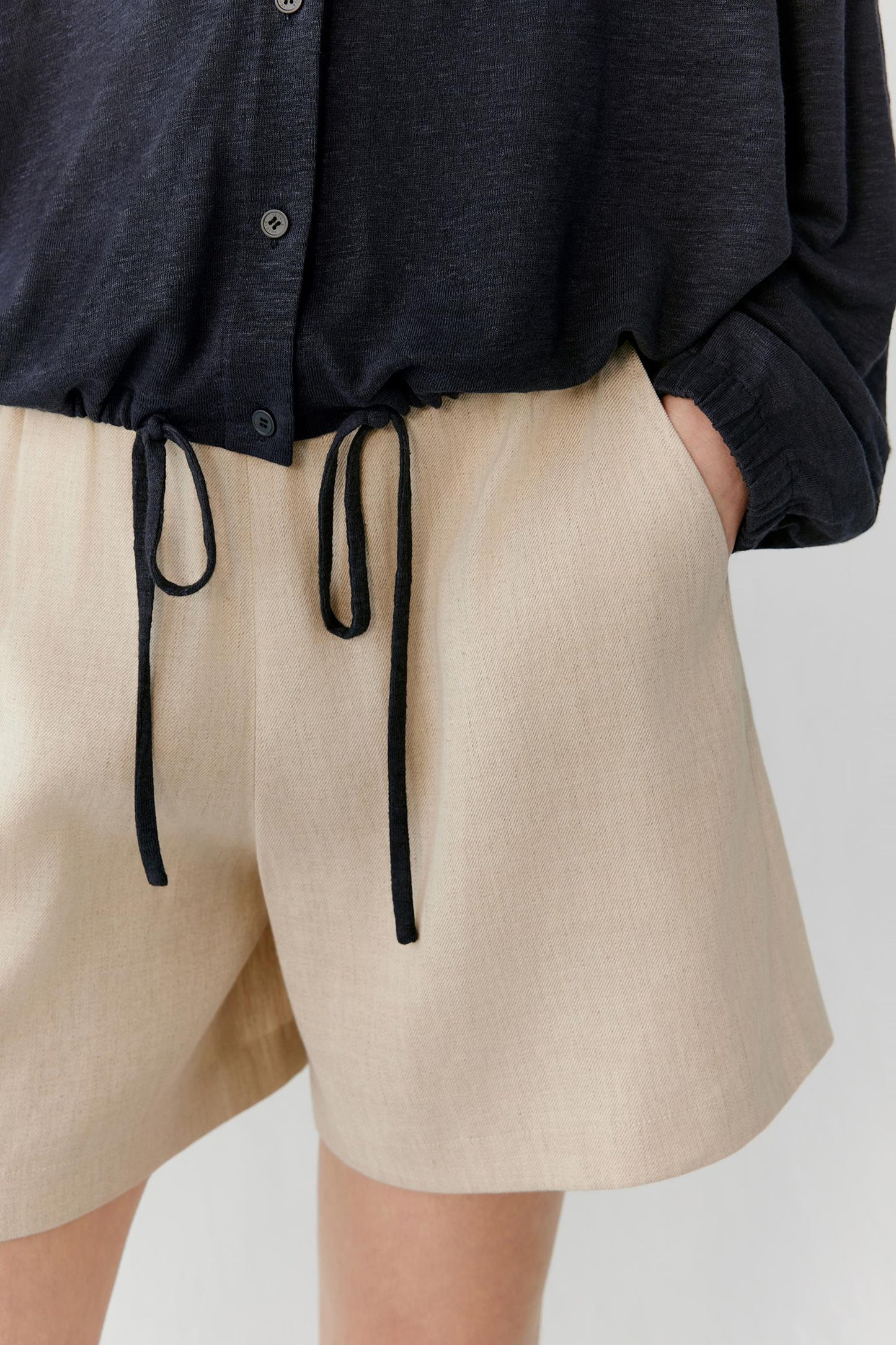 Close-up of the lower hem showing the adjustable drawstring, gathered hem construction and lightweight texture of the linen blend jersey. The image highlights the clean finishing and subtle drape of the fabric.