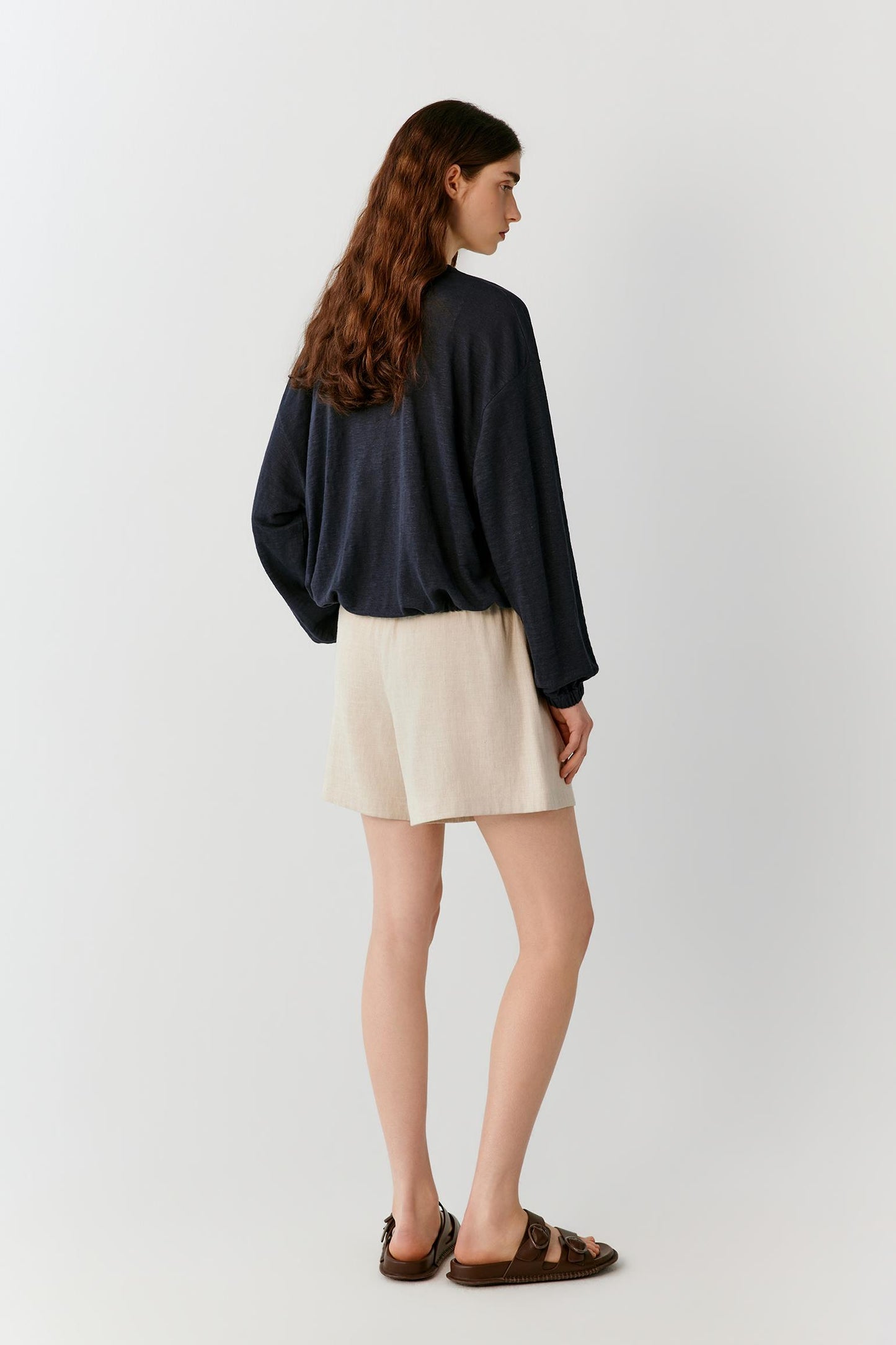 Three-quarter rear view highlighting the clean back construction, relaxed silhouette and fluid movement of the lightweight linen blend jersey. The image emphasizes the balanced proportions and understated design of the jacket.