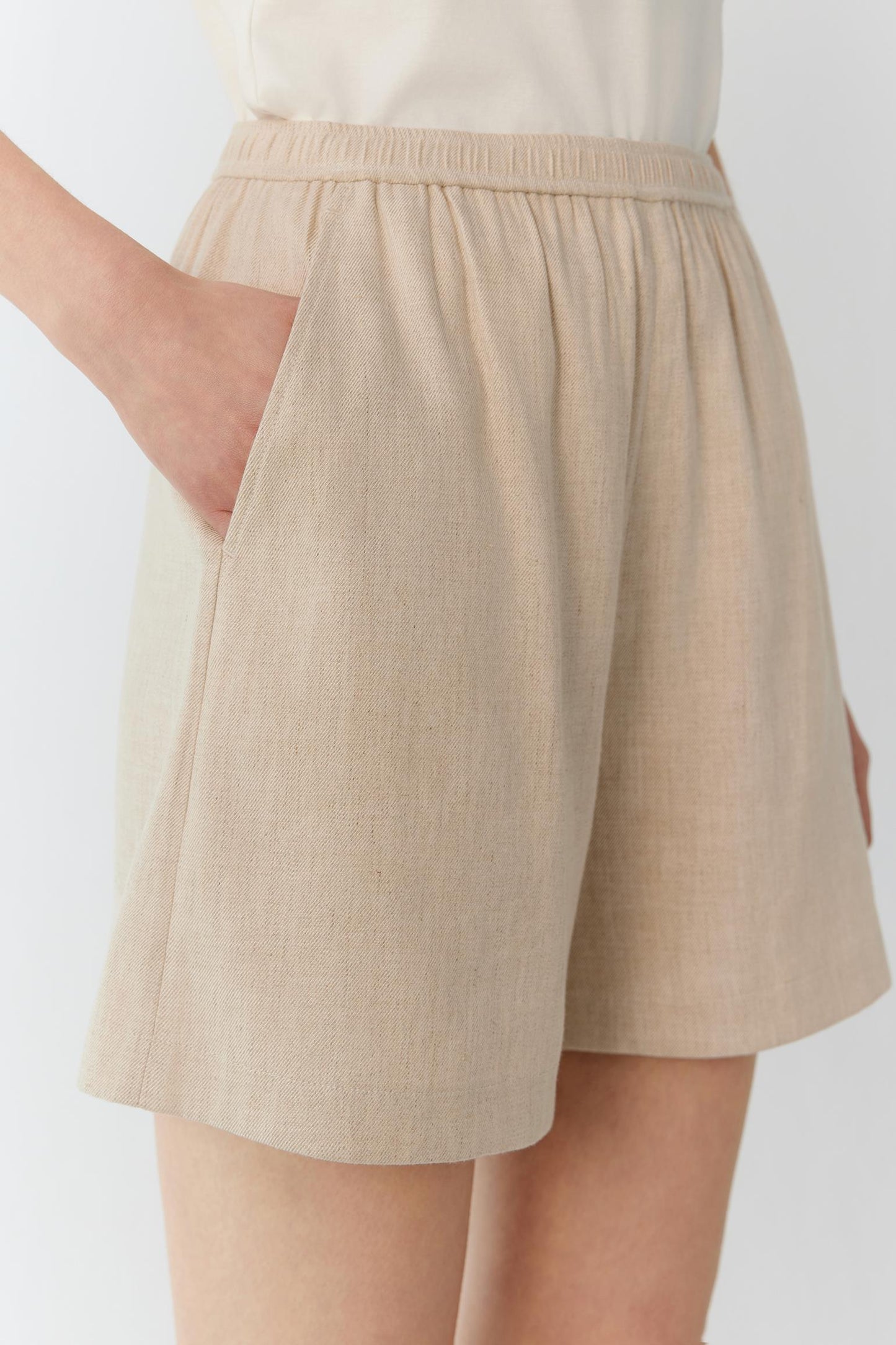 Side view highlighting the relaxed cut, fluid drape and lightweight structure of the fabric. The image emphasizes the clean side seam and the natural movement of the shorts when worn.