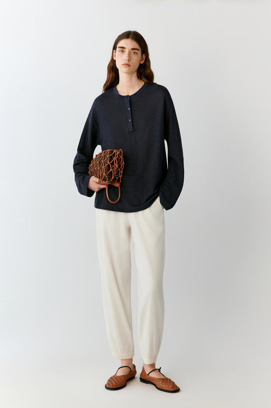 Front view of a woman wearing a deep navy top in a linen blend jersey, highlighting the relaxed silhouette, lightweight construction and fluid drape of the fabric. The smooth surface, round neckline and dropped shoulders create a clean, understated appearance.