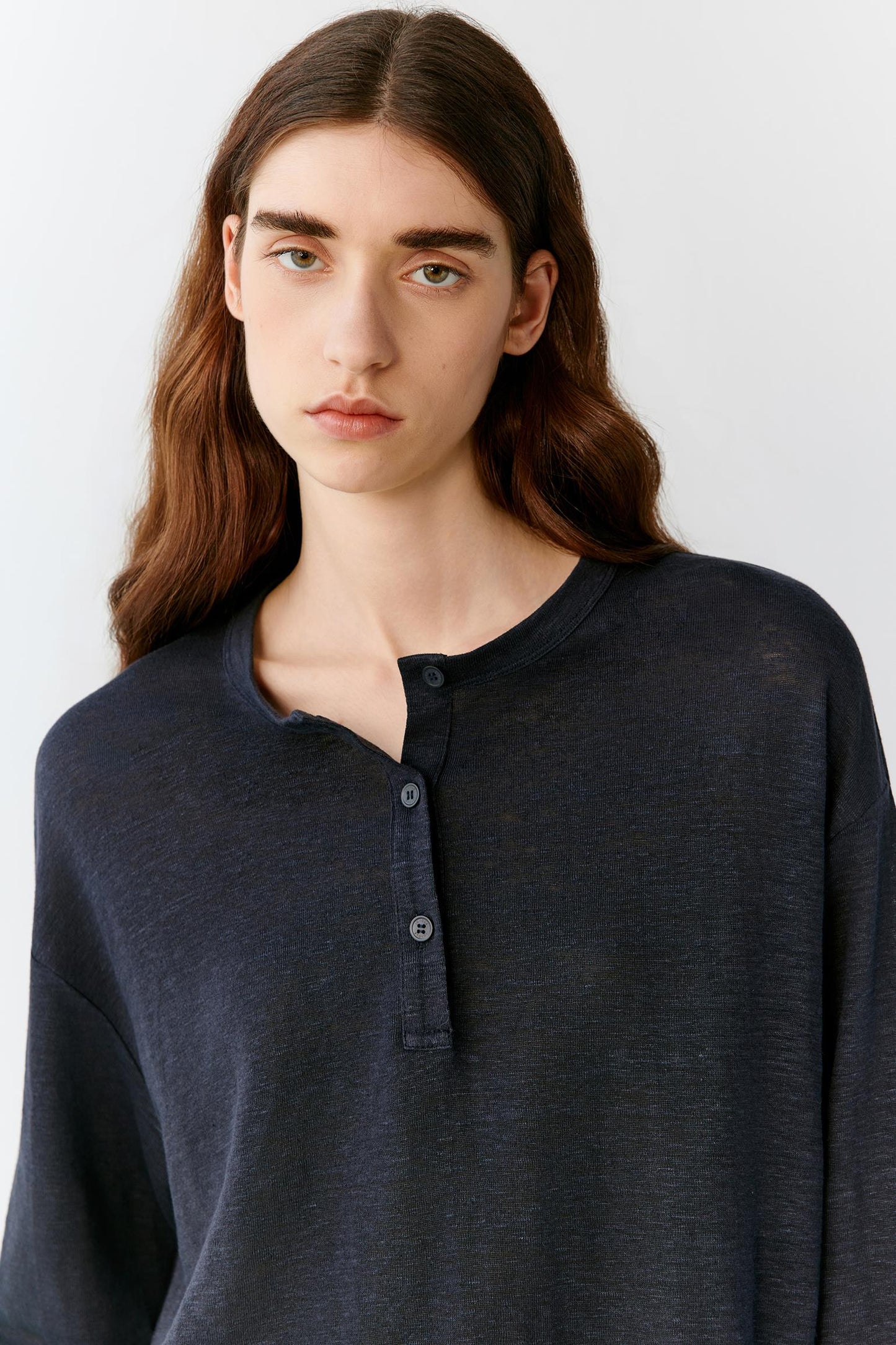 Close-up portrait focusing on the round neckline, dropped shoulders and upper body construction. The image reveals the smooth texture, soft hand and subtle depth of the deep navy jersey fabric.