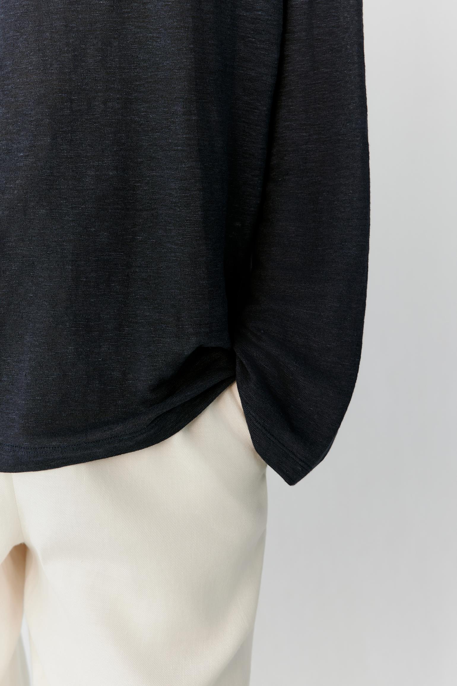 Close-up of the lower sleeve and side hem showing the clean finishing, side slit and lightweight structure of the linen blend jersey. The image highlights the fluid drape and understated construction details of the garment.