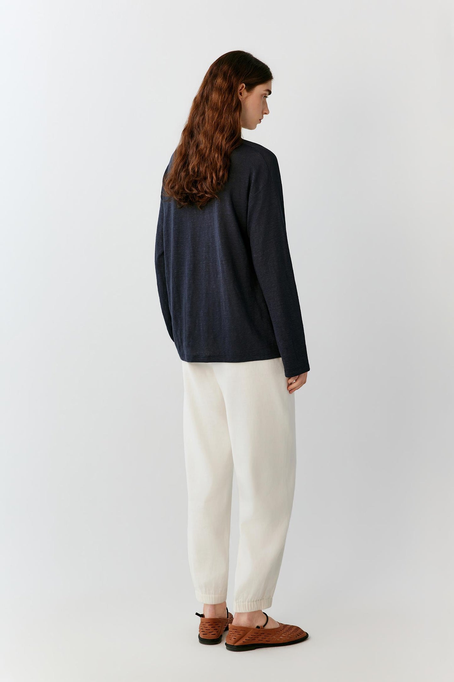 Three-quarter rear view highlighting the clean back construction, relaxed proportions and fluid movement of the lightweight jersey. The image emphasizes the soft drape of the fabric and the balanced silhouette from the back.