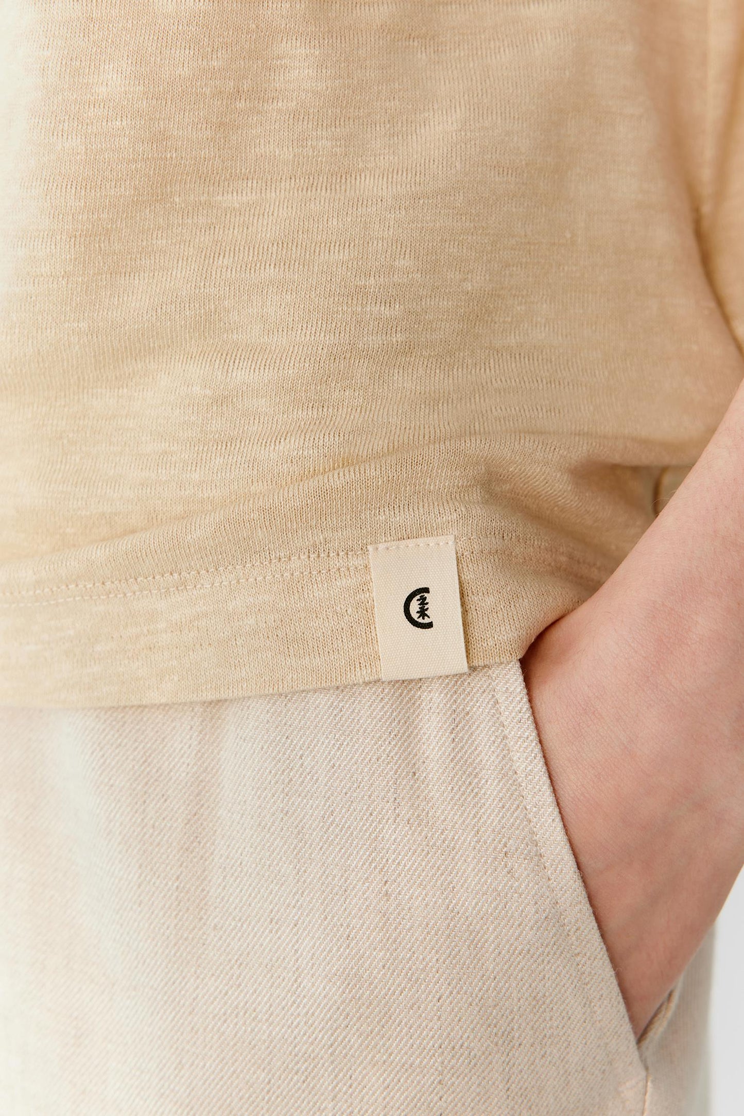 Close-up of the lower side of the garment showing the side slit, clean hem finishing and fine texture of the linen blend jersey. The image reveals the subtle weave, lightweight construction and soft hand of the fabric.