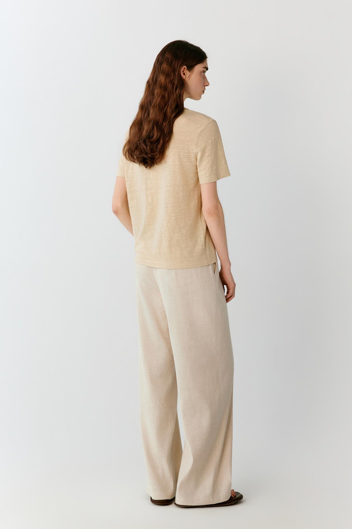 Three-quarter rear view highlighting the clean back construction, relaxed fit and fluid drape of the linen blend jersey. The image emphasizes the natural movement of the fabric and the balanced proportions of the silhouette.