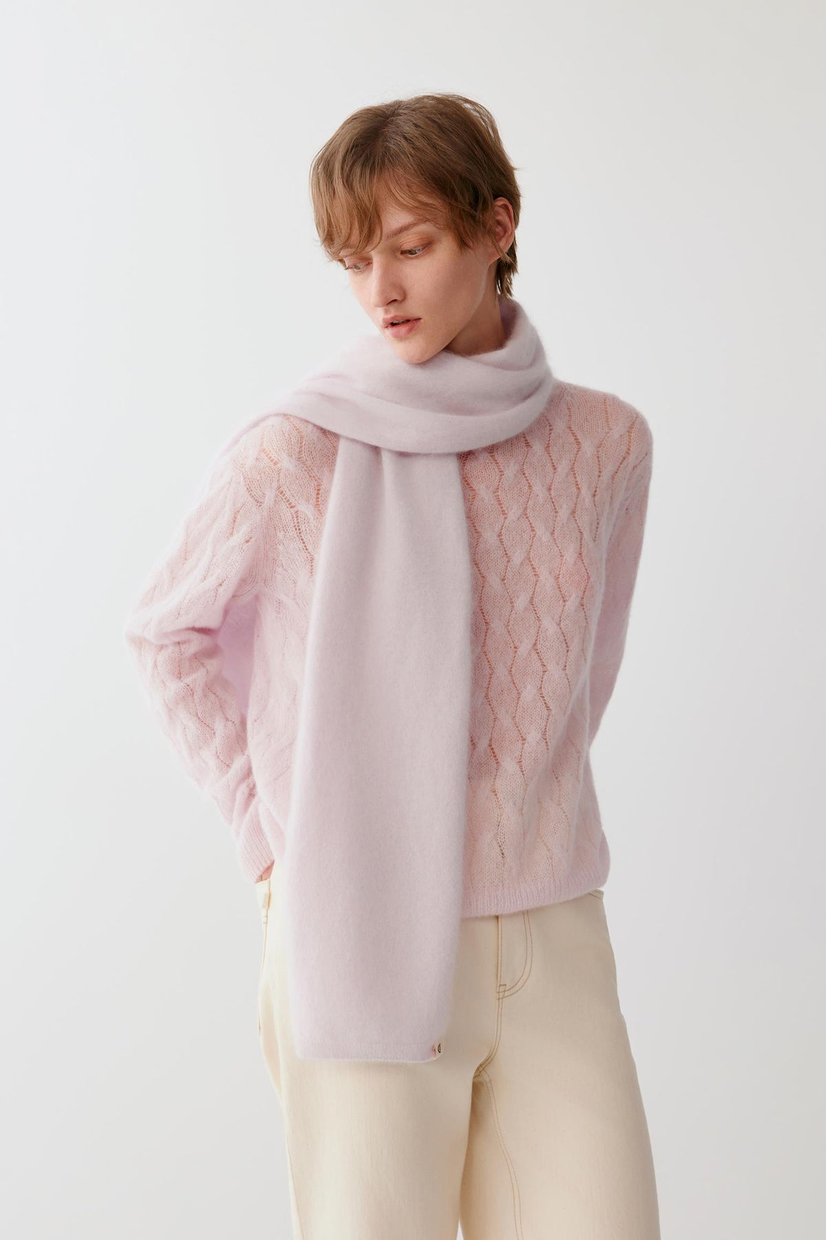 Front view of a woman wearing a light pink brushed cashmere scarf wrapped around the neck, showing the long draped ends and brushed texture.