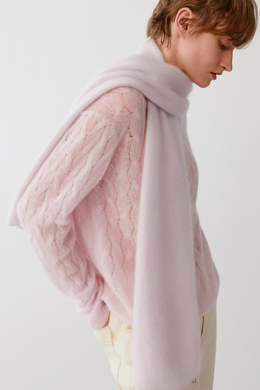 Side view of a woman wearing the light pink brushed cashmere scarf, showing the long draped ends and brushed texture.