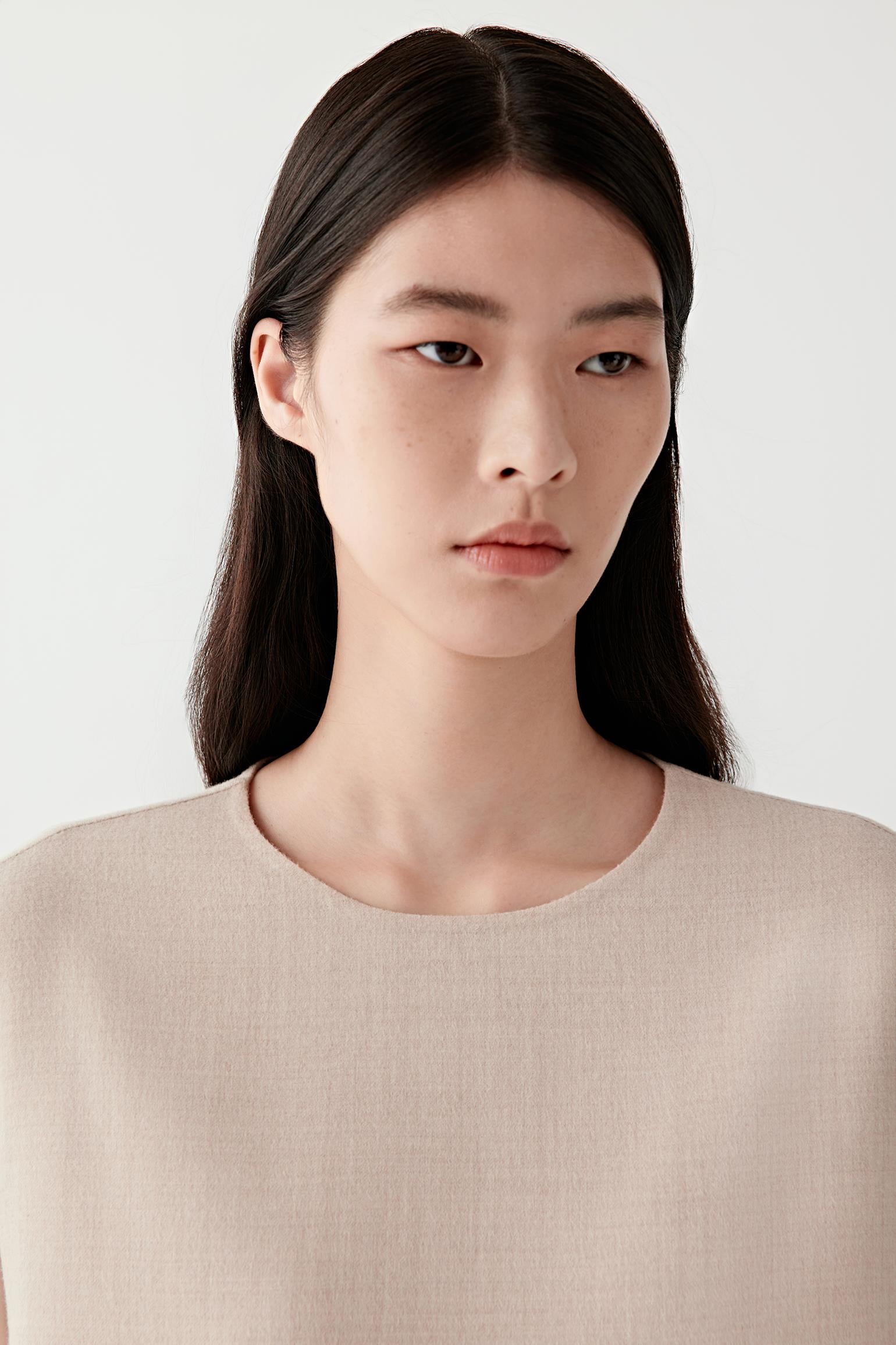 Close-up of the upper part of the dress showing the round neckline, sleeveless shoulder line and the smooth lightweight wool fabric.