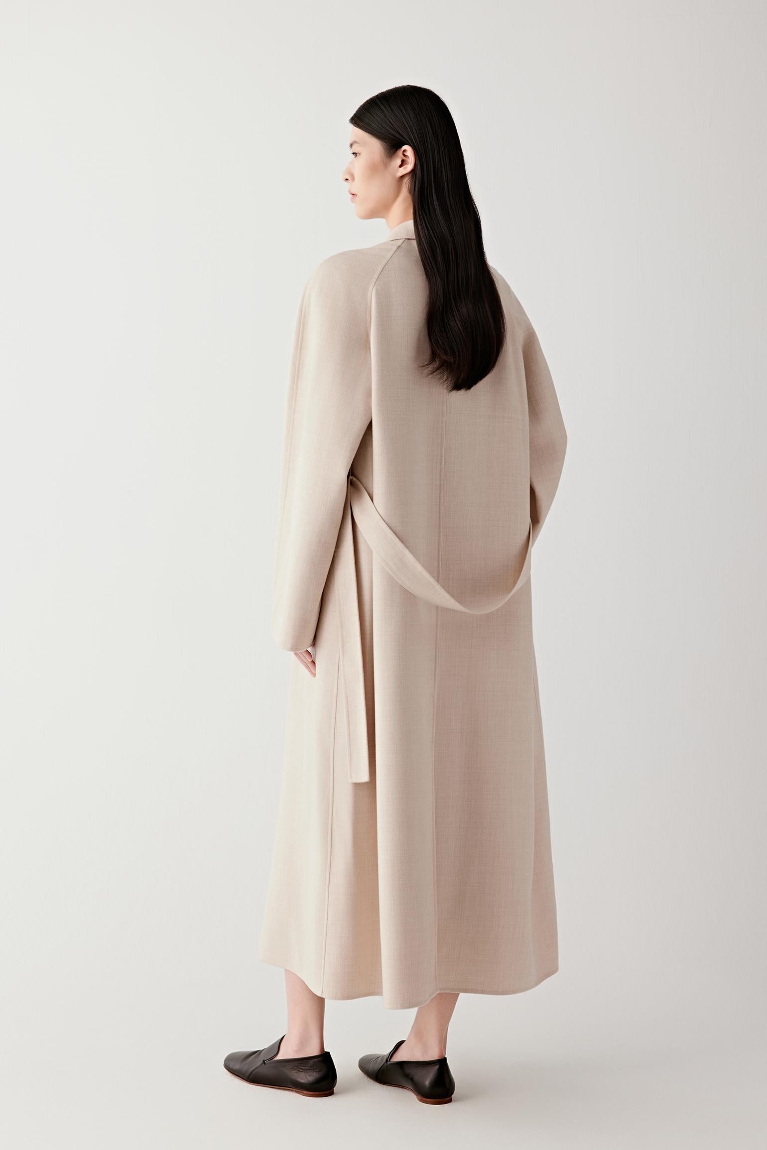 Back view of the coat showing its fluid drape and mid-calf length.