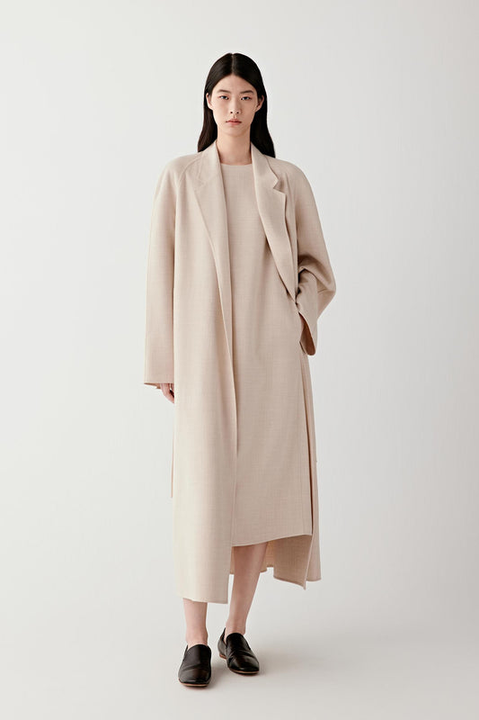 Woman wearing a long beige lightweight wool coat, front view with relaxed fit.