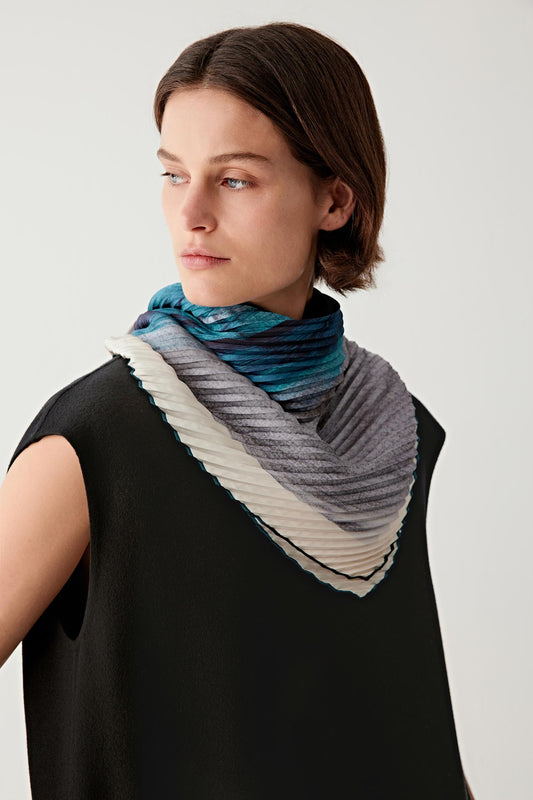 Woman wearing a blue gradient silk twill scarf layered over a sleeveless black dress.