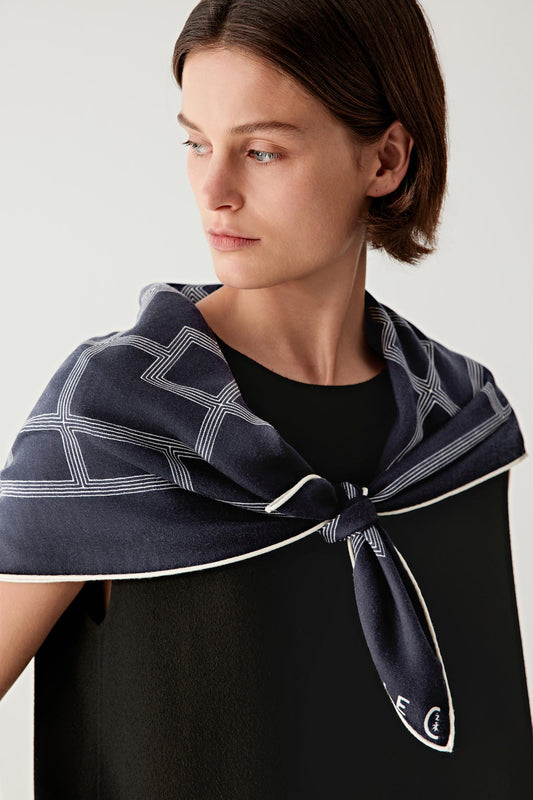 Three-quarter view of the scarf worn, highlighting the fluid drape and structured geometric desig