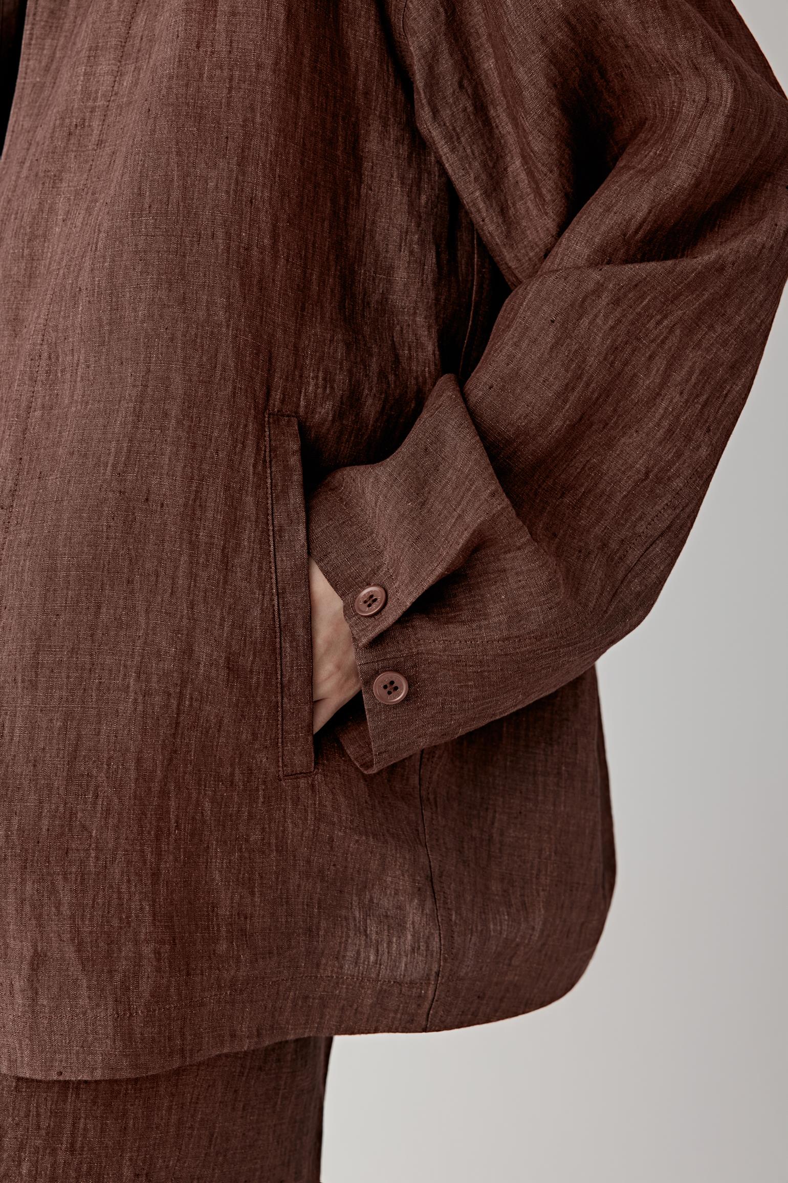 Close-up of the sleeve and side seam showing stitching lines, fabric density and the soft yet structured feel of the woven linen
