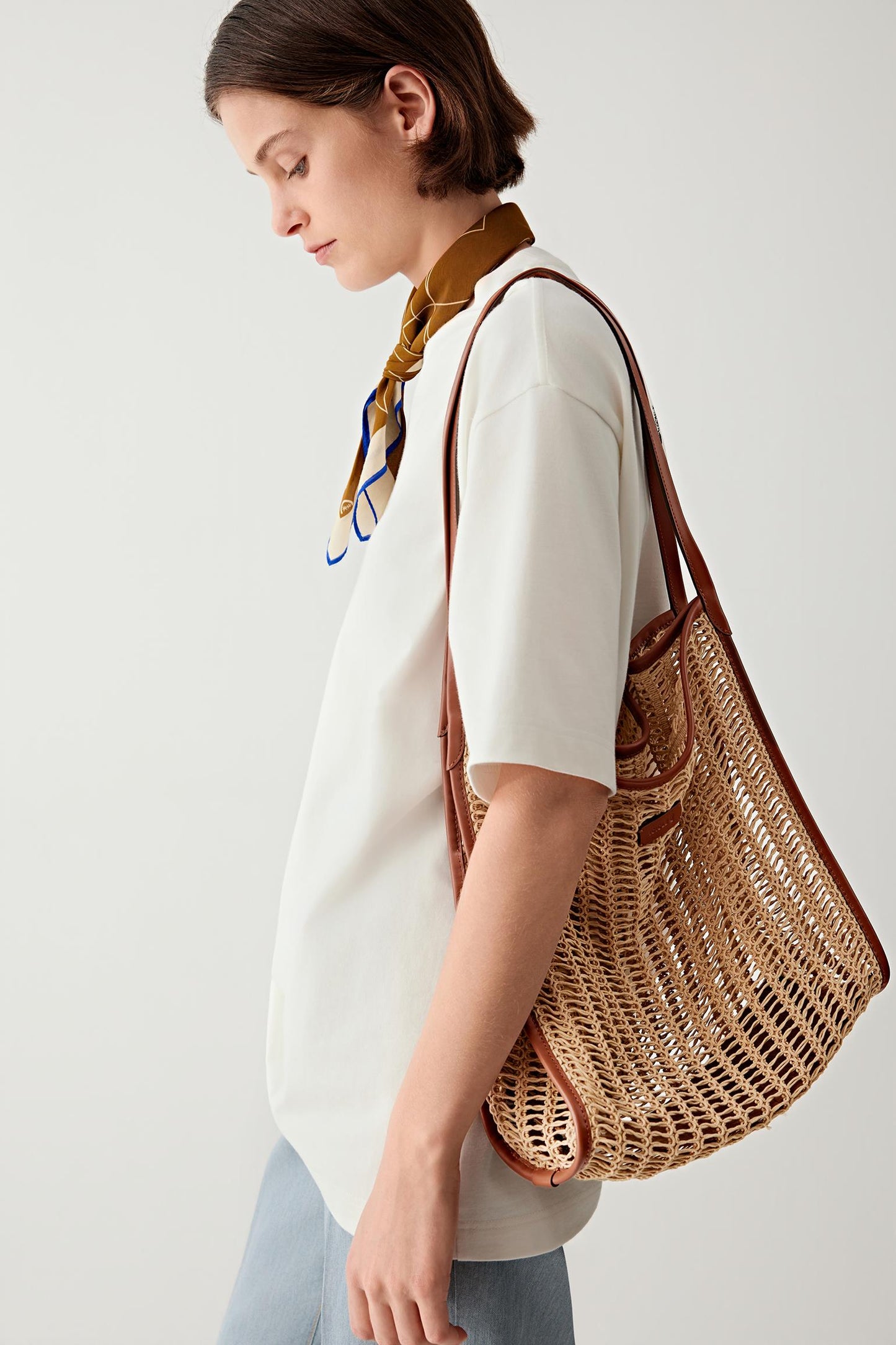 Side view of the tote bag worn on the shoulder, showing how the mesh expands with contents, emphasizing volume, flexibility and everyday use