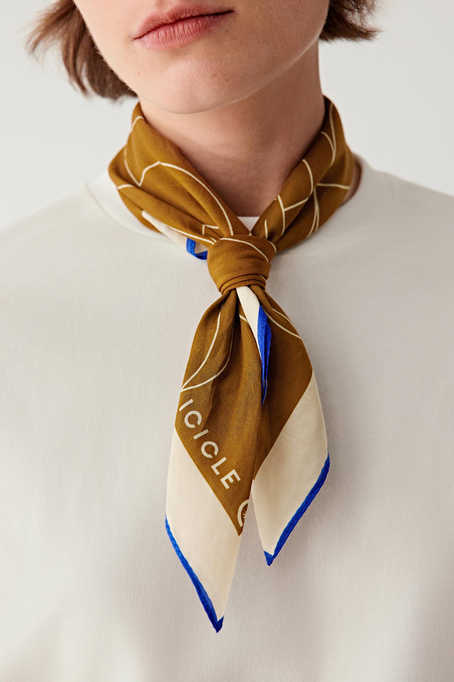 Person wearing a mustard yellow scarf with blue border and 'Ciclo' branding on a white background