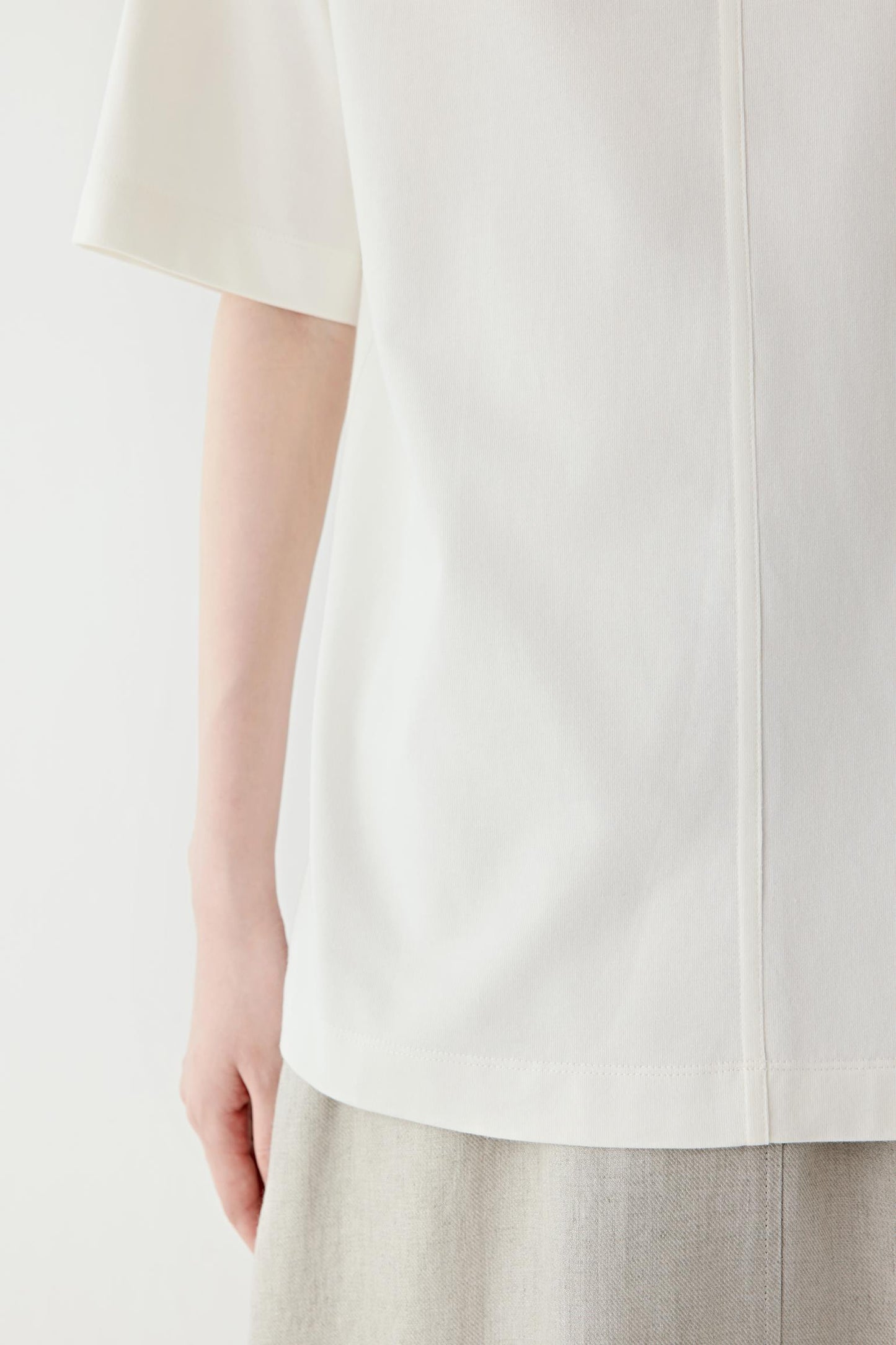 Close-up of the sleeve and fabric surface showing the lightweight jersey weave, clean finishing and softly fluid drape characteristic of cotton jersey.