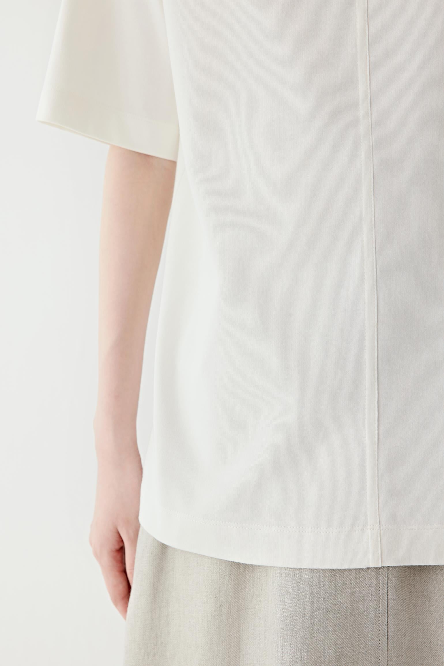 Close-up of the sleeve and fabric surface showing the lightweight jersey weave, clean finishing and softly fluid drape characteristic of cotton jersey.