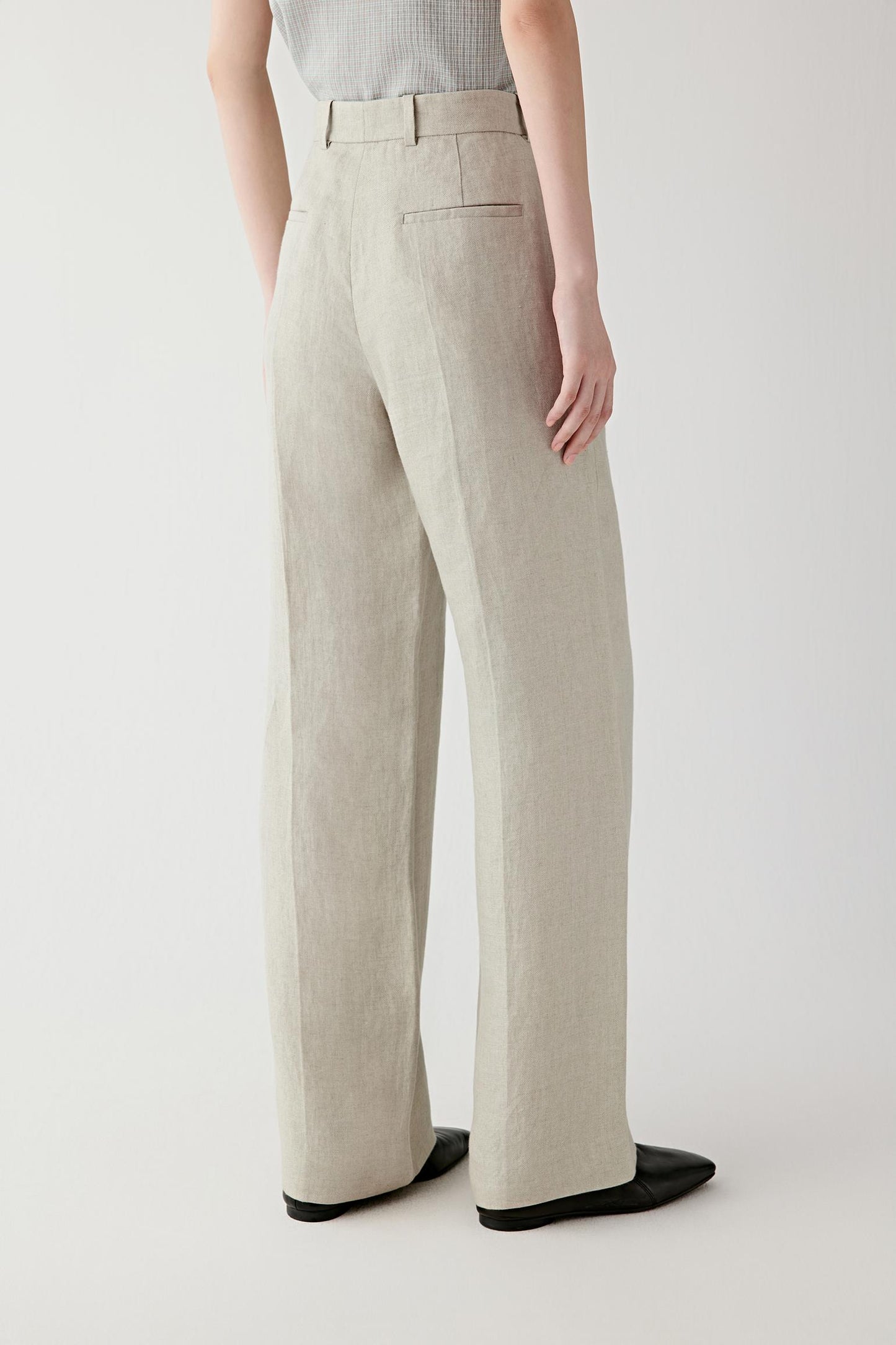 Side or back view emphasizing the clean straight-leg construction and lightly structured drape of the linen twill fabric. The material falls softly while retaining shape and definition.