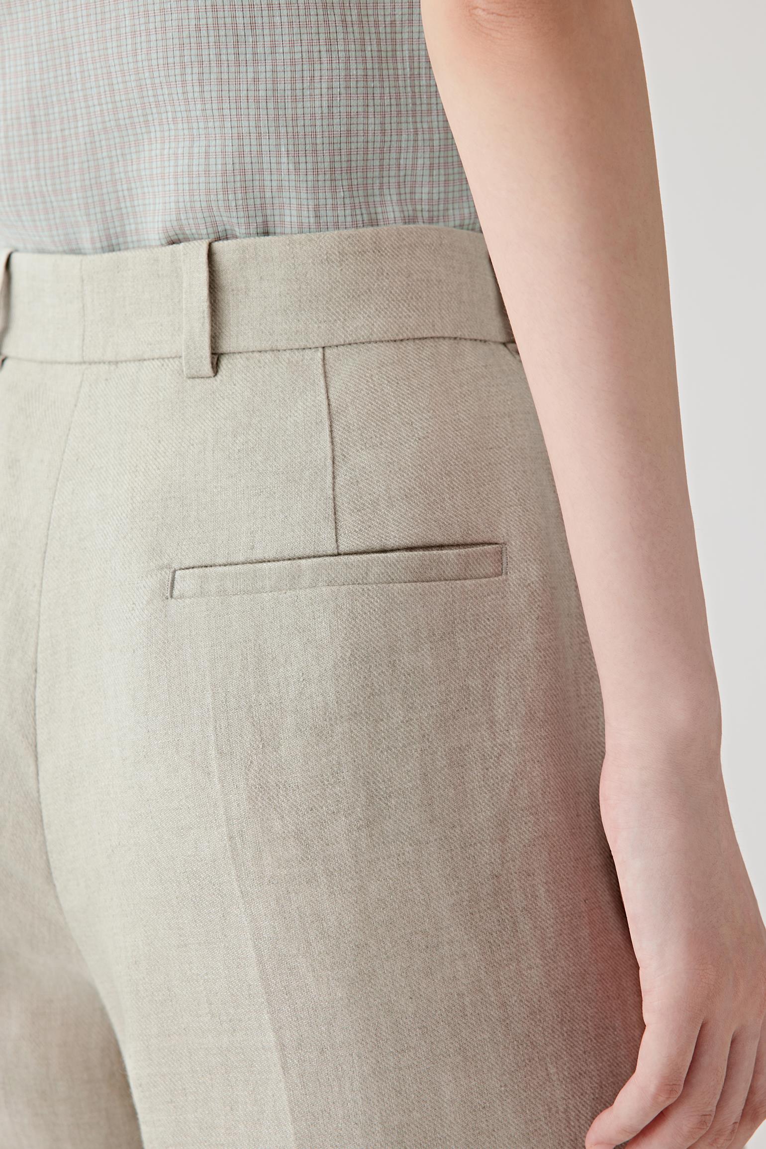 Close-up of the pressed creases and pocket construction showing the visible grain, dry hand and softly structured quality characteristic of linen twill.